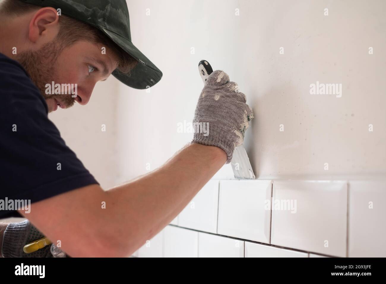 joven hombre utilizando espátula y enlucido de pared con blanco