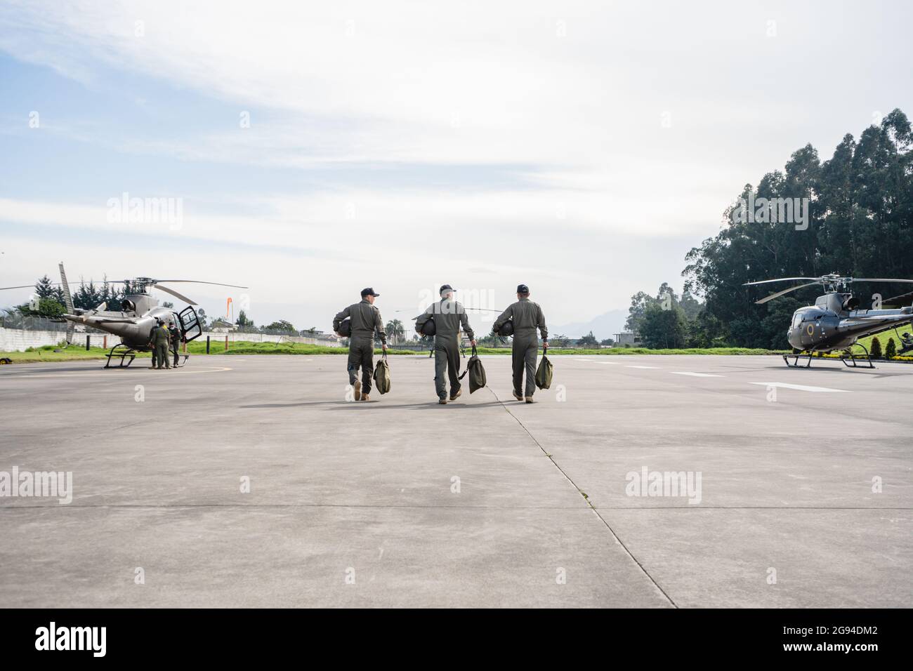 tres militares caminando en una pista hacia los helicópteros Foto de stock