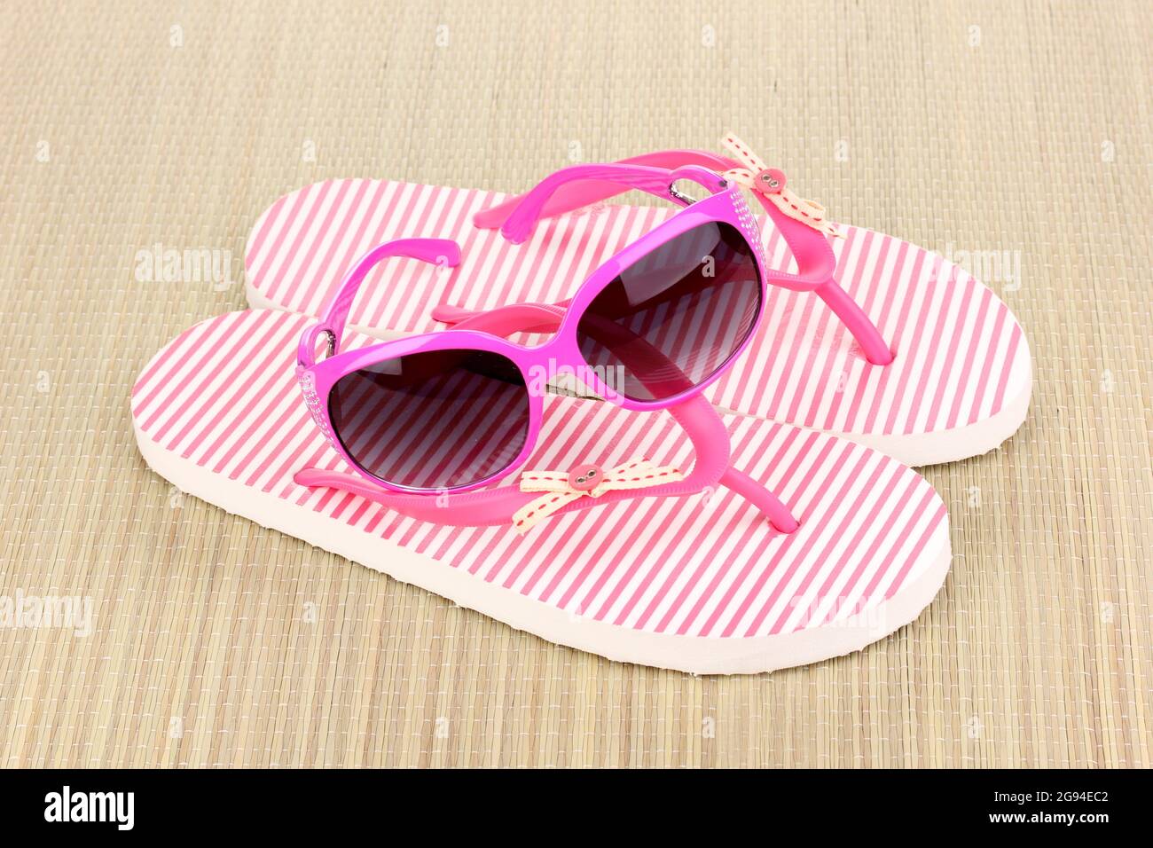 Pantuflas de playa de color rosa con gafas de sol en la alfombrilla  Fotografía de stock - Alamy