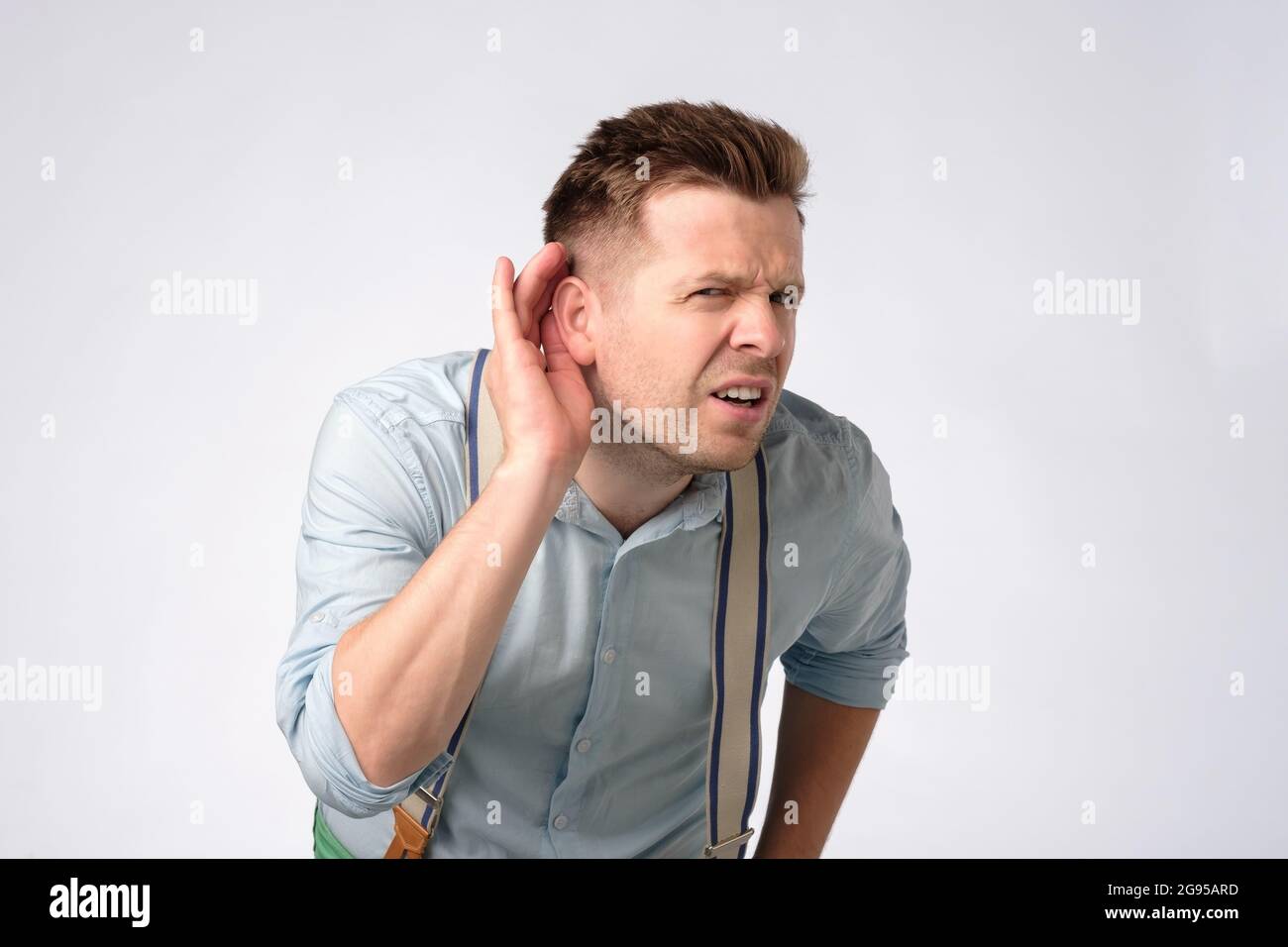 Hombre poniendo la mano cerca del oído escuchando un sonido silencioso o prestando atención Foto de stock
