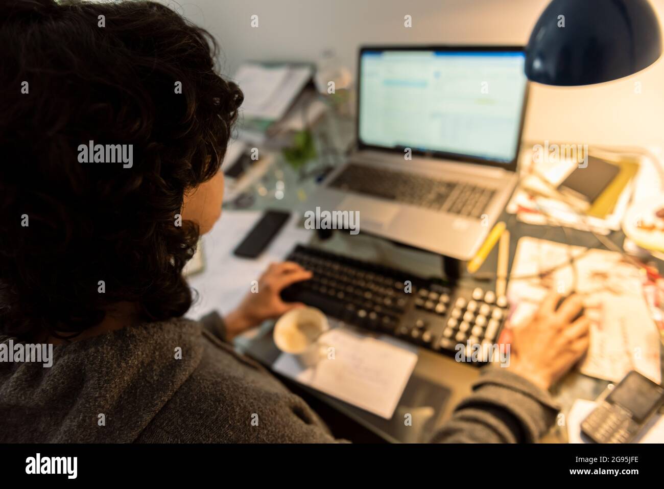 la mujer joven trabaja en línea en casa con ordenador y teclado frontal de taza de café Foto de stock