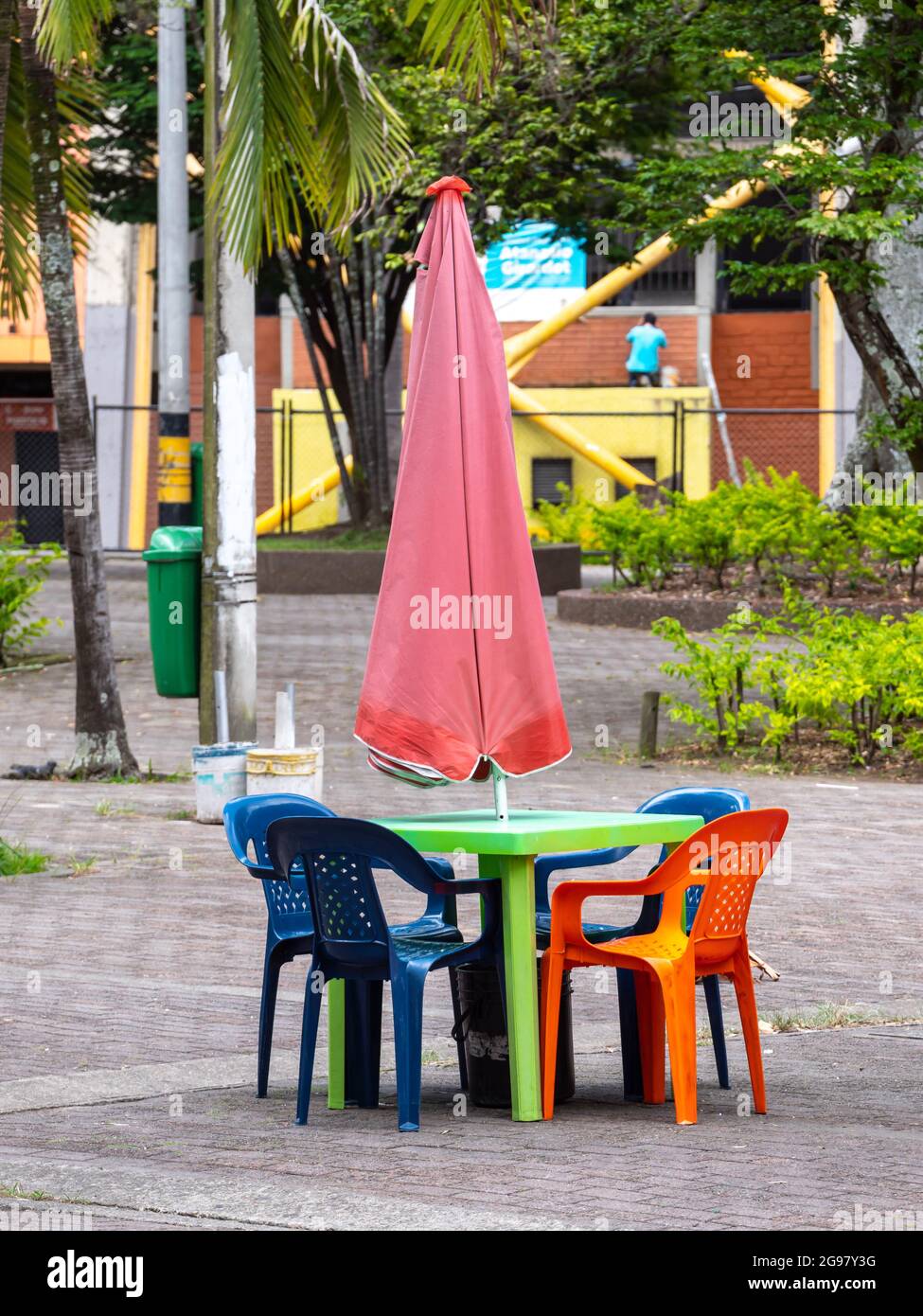 Juego vacío de mesa y sillas de plástico con paraguas en un parque verde en  Medellín, Colombia Fotografía de stock - Alamy