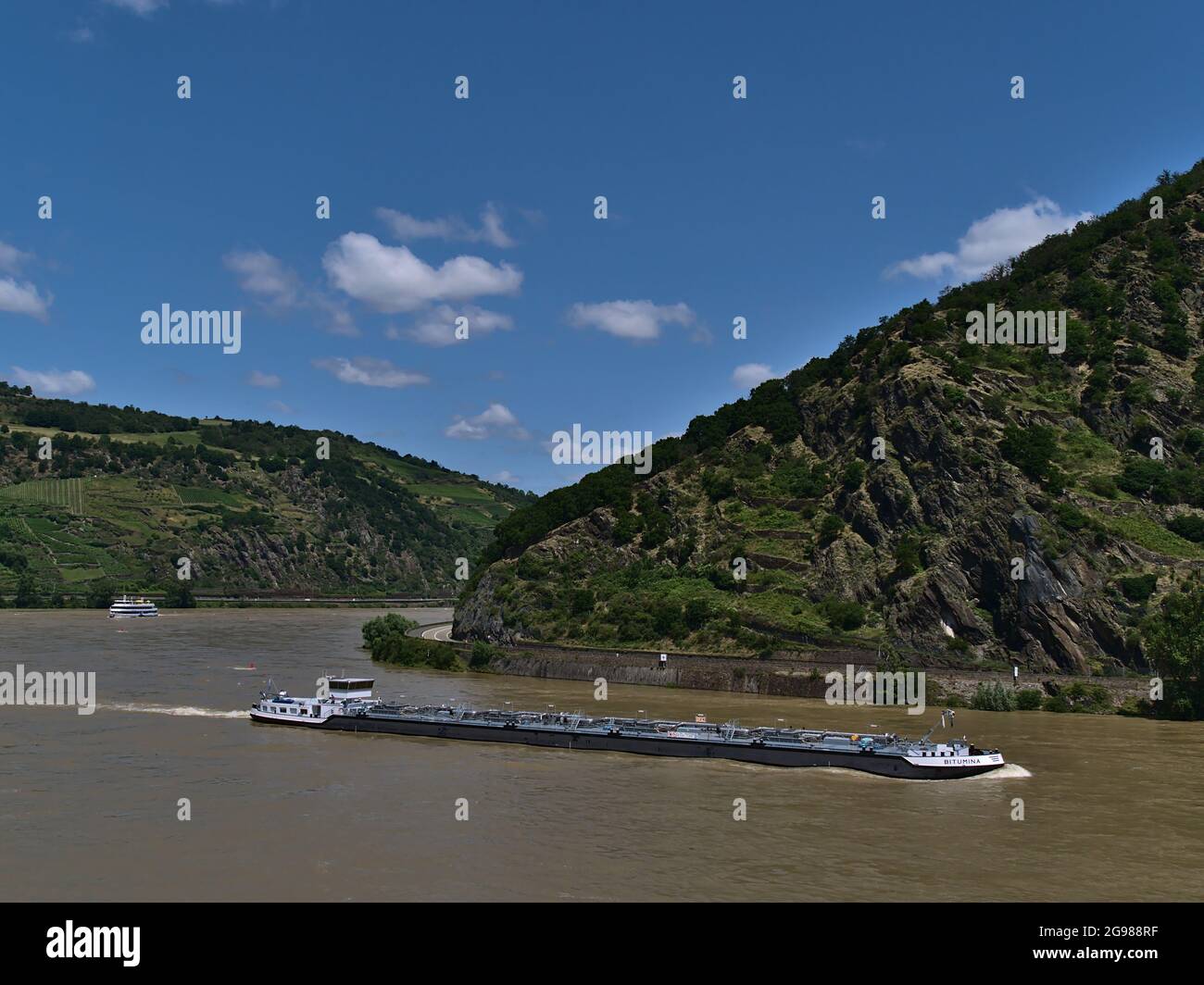 Hermoso paisaje con el río Rin rodeado de laderas rocosas con barcaza de carga pasando por y excursión en barco de crucero en el fondo en el día soleado. Foto de stock