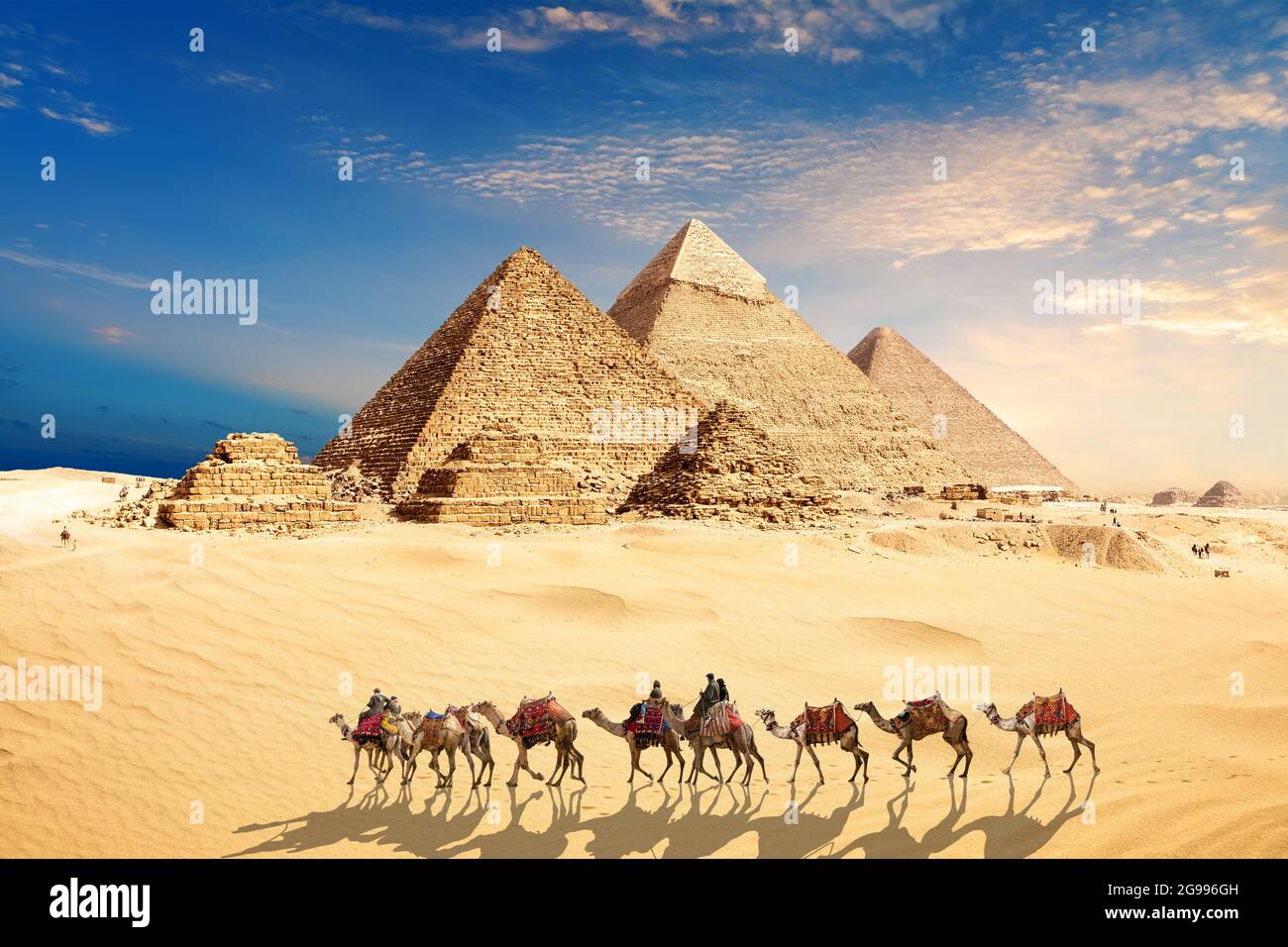 Una caravana de camellos con beduinos por las Pirámides de Egipto en el desierto de Giza Foto de stock
