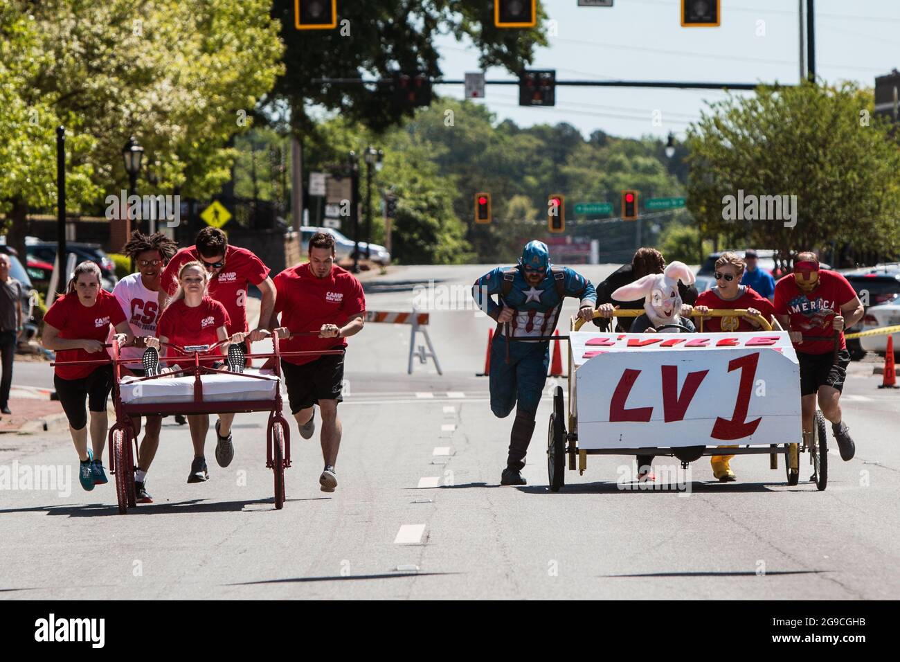 Lawrenceville, GA, EE.UU. - 27 de abril de 2019: Dos equipos empujan camas caseras sobre ruedas por una calle en un evento de carrera de cama para beneficiar a la caridad. Foto de stock