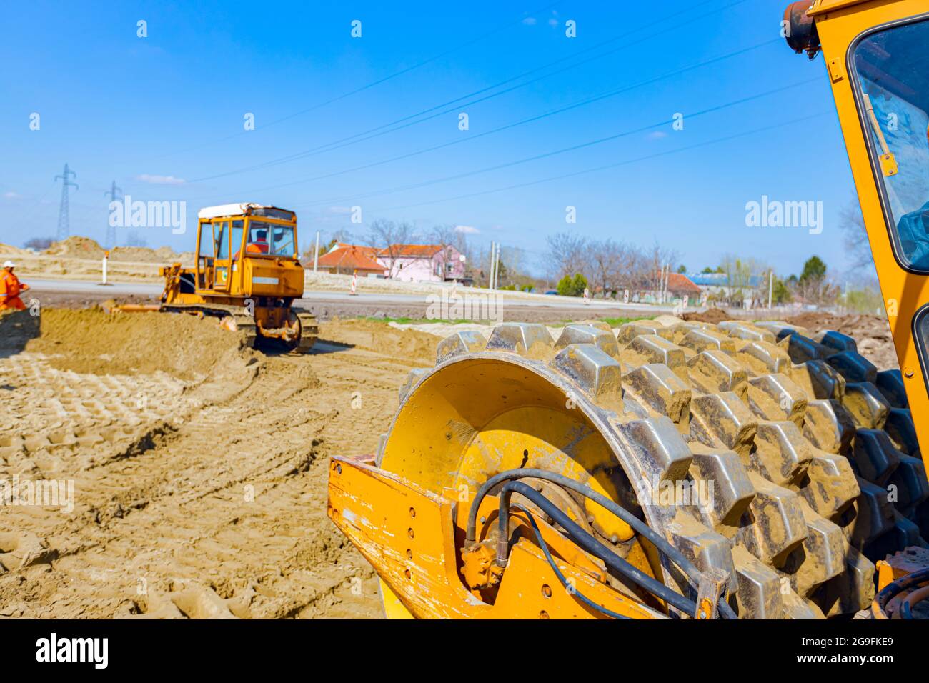 Vista sobre el rodillo de la carretera con los picos vibrando, el  compactador está compactando, apisonando arena para la fundación de la  carretera en el sitio de la construcción Fotografía de stock -