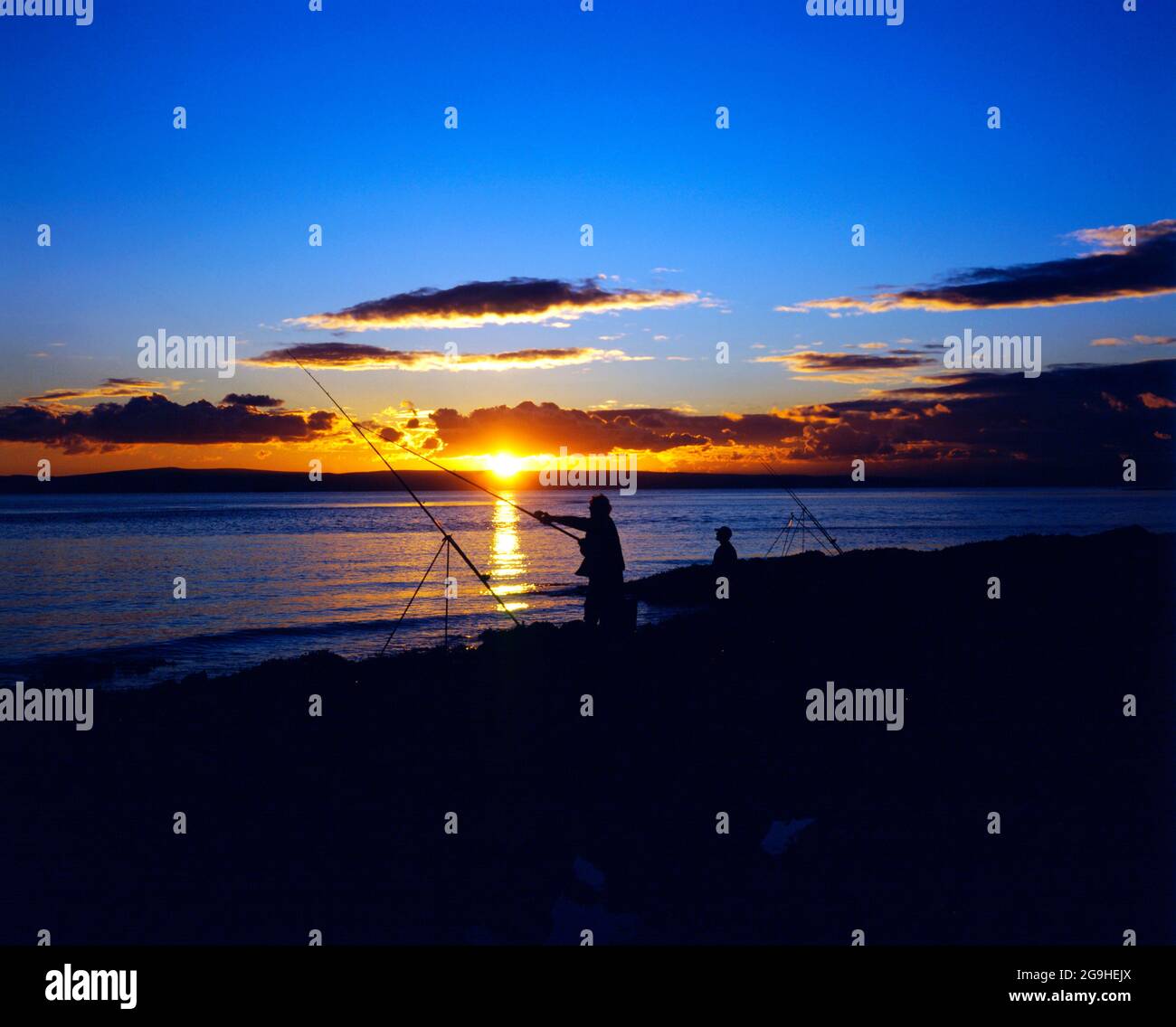 Pescador y puesta de sol, Canal de Bristol, Isla Barry, Gales del Sur. Foto de stock