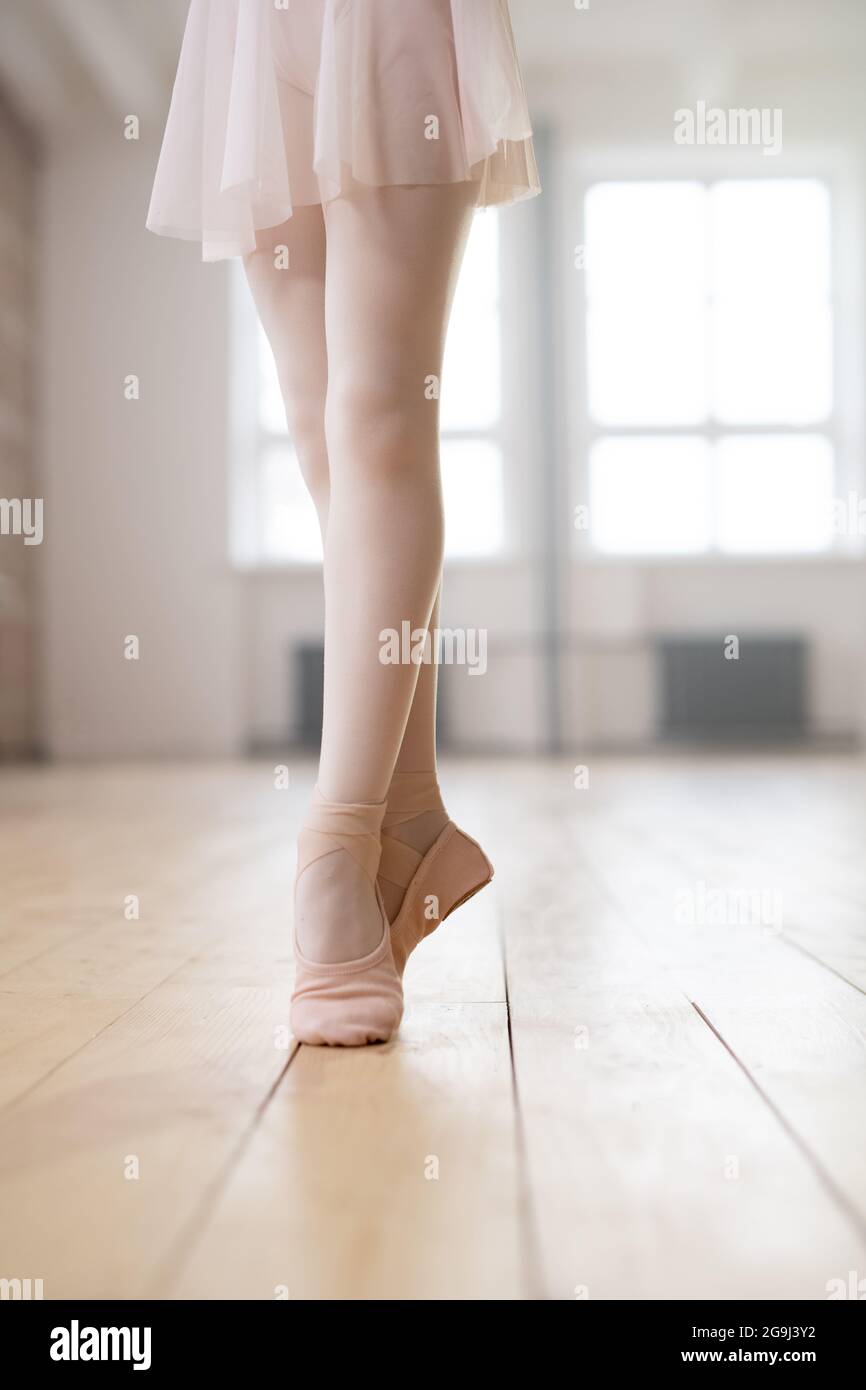 pequeña bailarina de pie sobre sus dedos de los pies y entrenando en la sala de baile Foto de stock