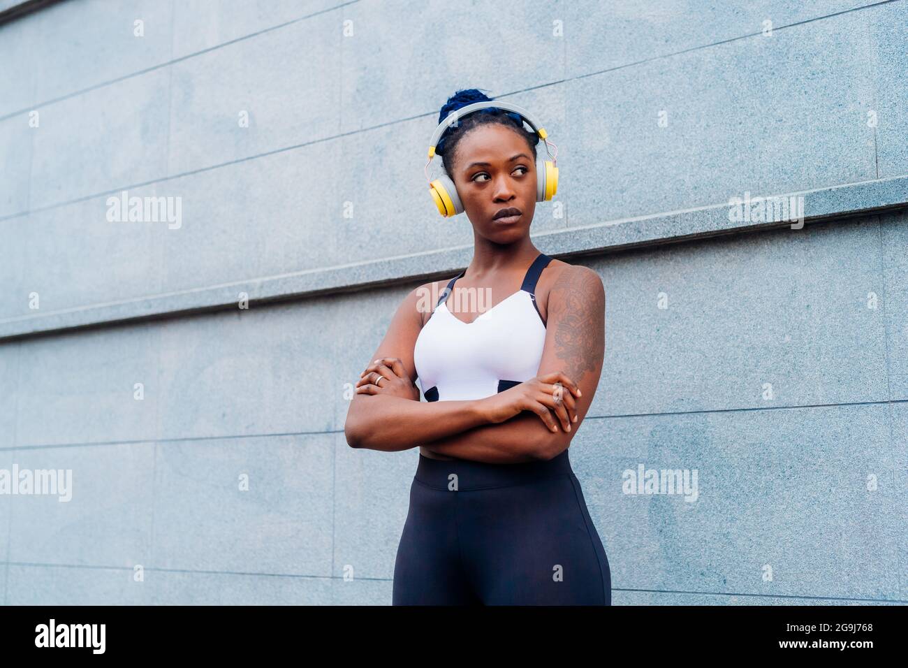 Italia, Milán, Retrato de mujer en sujetador deportivo y auriculares en la ciudad Foto de stock