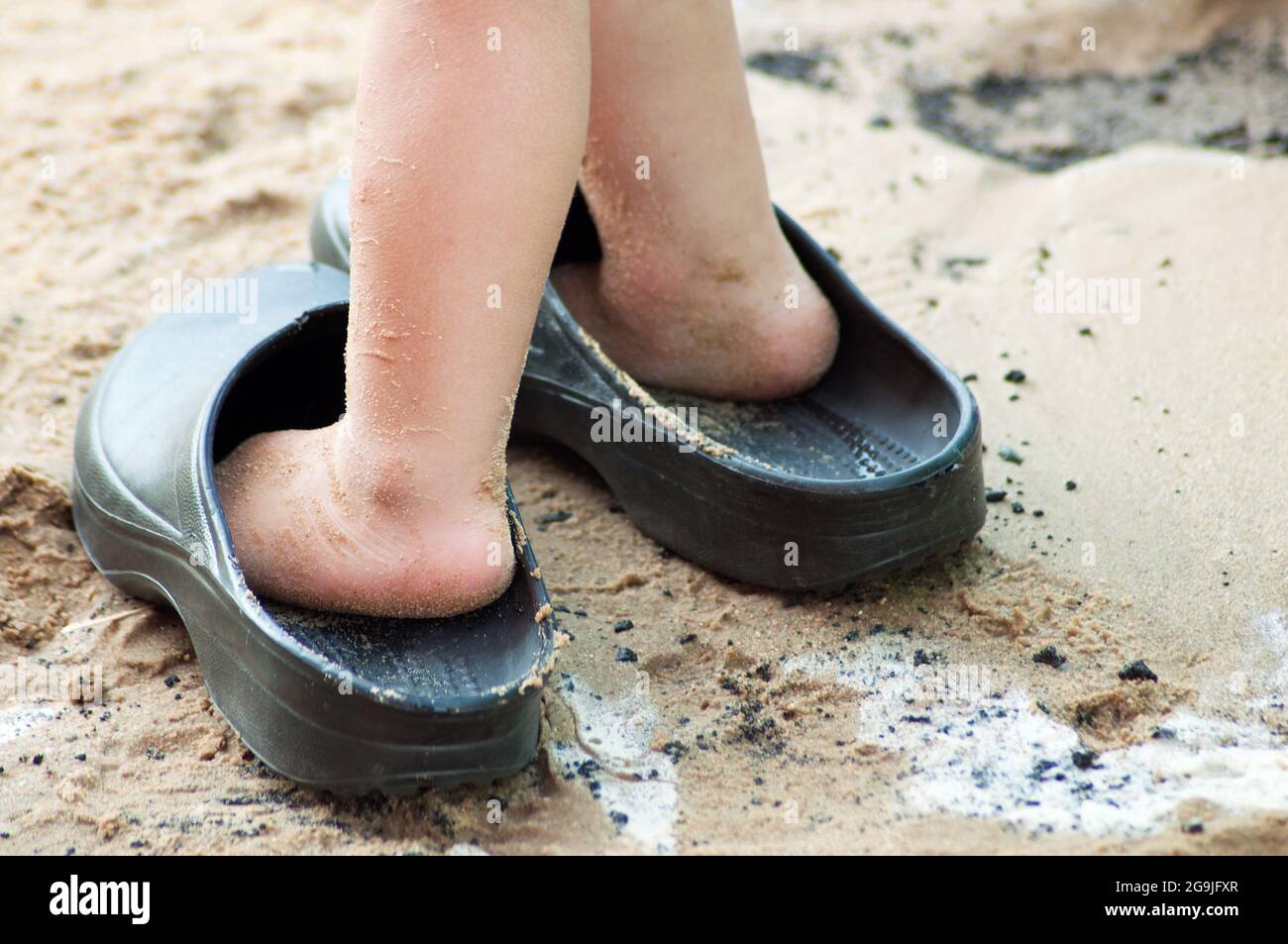 pies del niño en sandalias grandes sobre arena húmeda Fotografía de stock -  Alamy