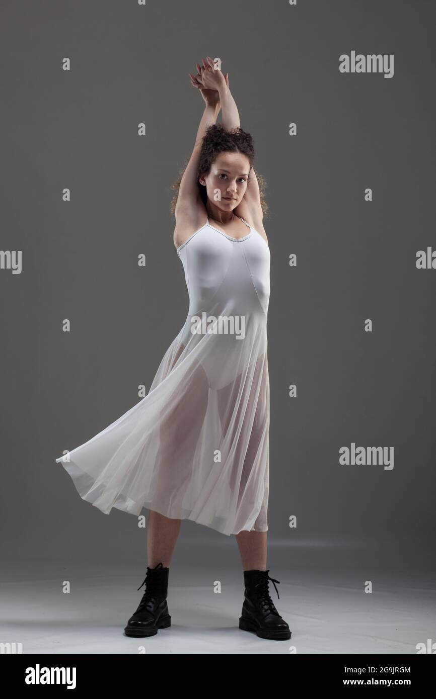 Chica con cabello rizado haciendo poses ballet. Bailarina en vestido blanco  y botas negras Fotografía de stock - Alamy