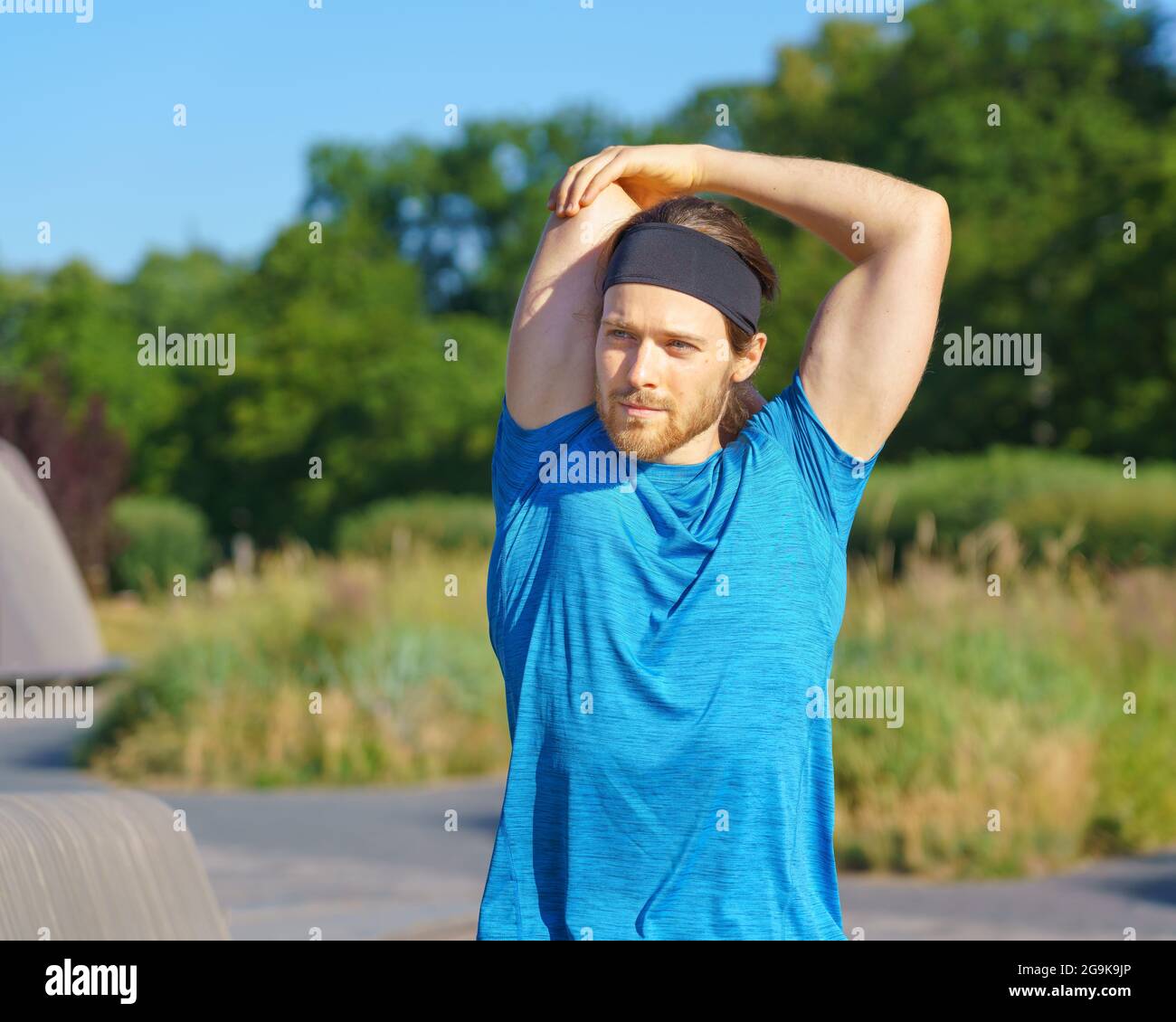 Joven hombre deportivo en ropa deportiva calentándose en la naturaleza en  el día soleado Fotografía de stock - Alamy