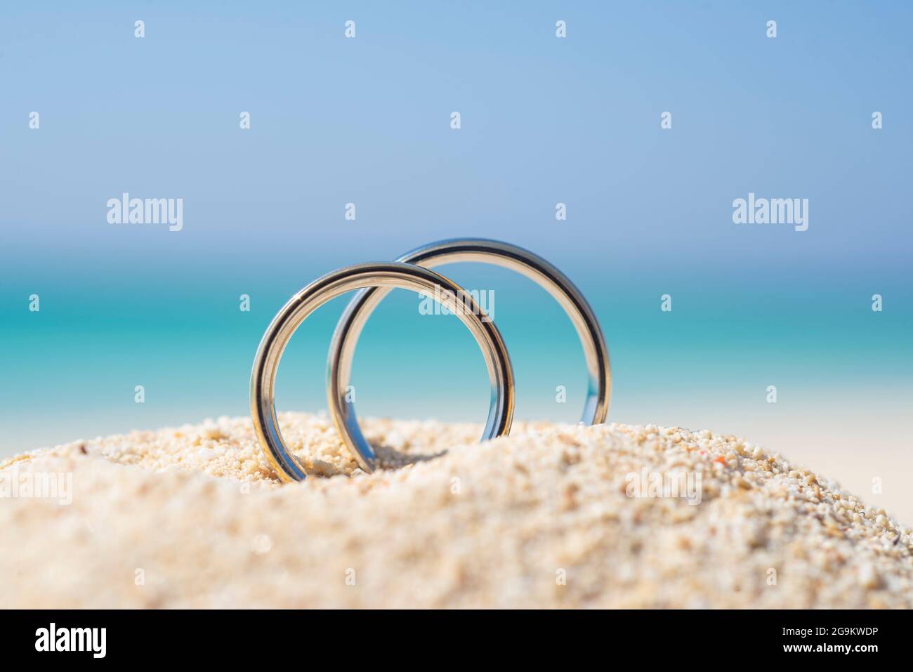 Par de anillos de boda de oro blanco joyas en arena en la playa tropical de  la isla del desierto durante el verano con fondo azul del océano Fotografía  de stock -