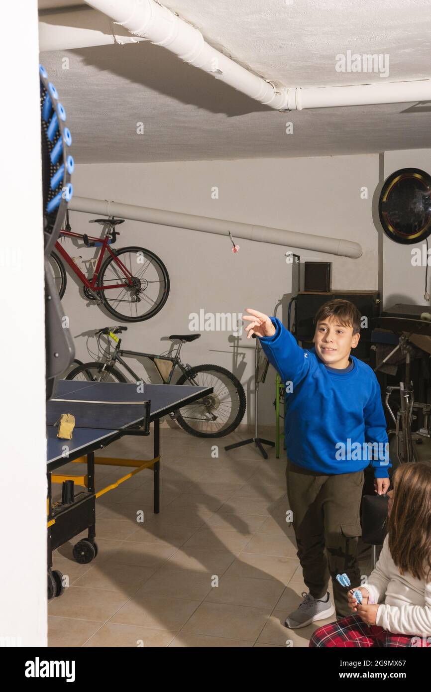 AYORA-VALENCIA, ESPAÑA - 17 de julio de 2021: Adolescente caucásico jugando  dardos en casa. Niña observándolo. Concepto de entretenimiento Fotografía  de stock - Alamy