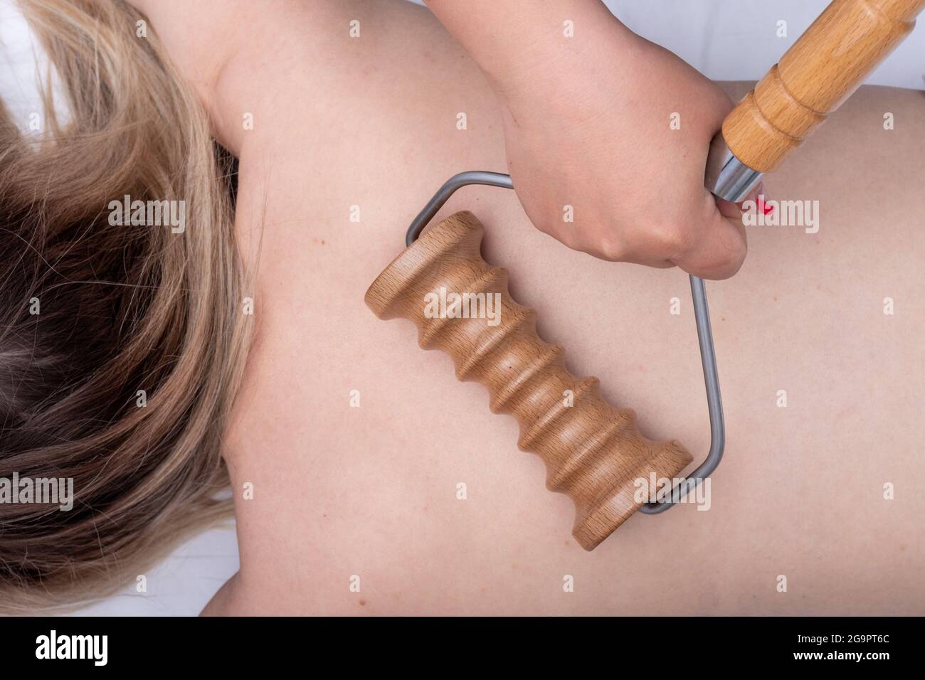 Manos del masajeador masajeando la espalda del paciente con un masajeador  de rodillo de madera, primer plano. Mujer con masaje en el spa en el salón  de belleza. Tratamiento del bac Fotografía