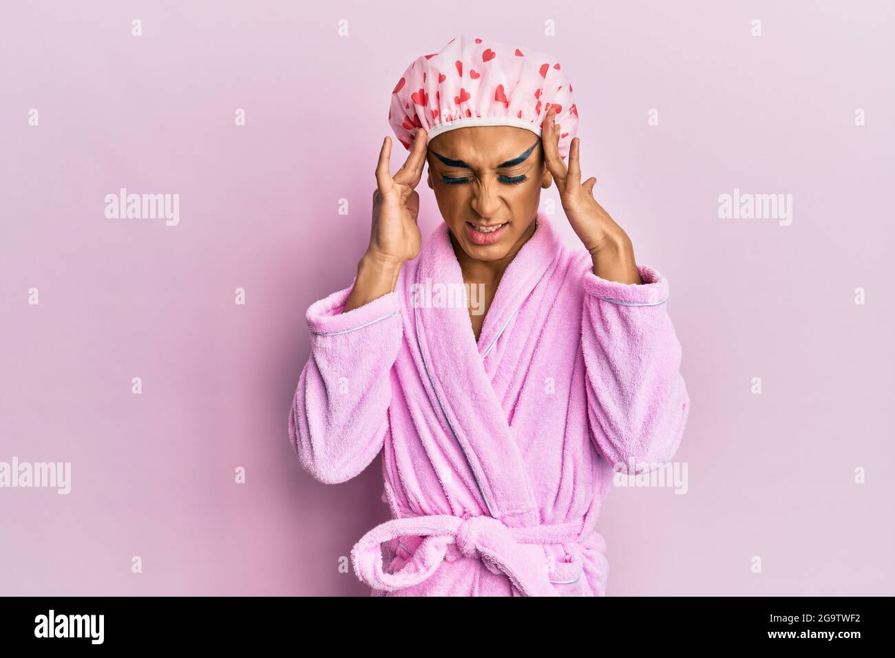Hombre hispano con gorro de ducha y albornoz con la mano en la cabeza,  dolor de cabeza por estrés Fotografía de stock - Alamy