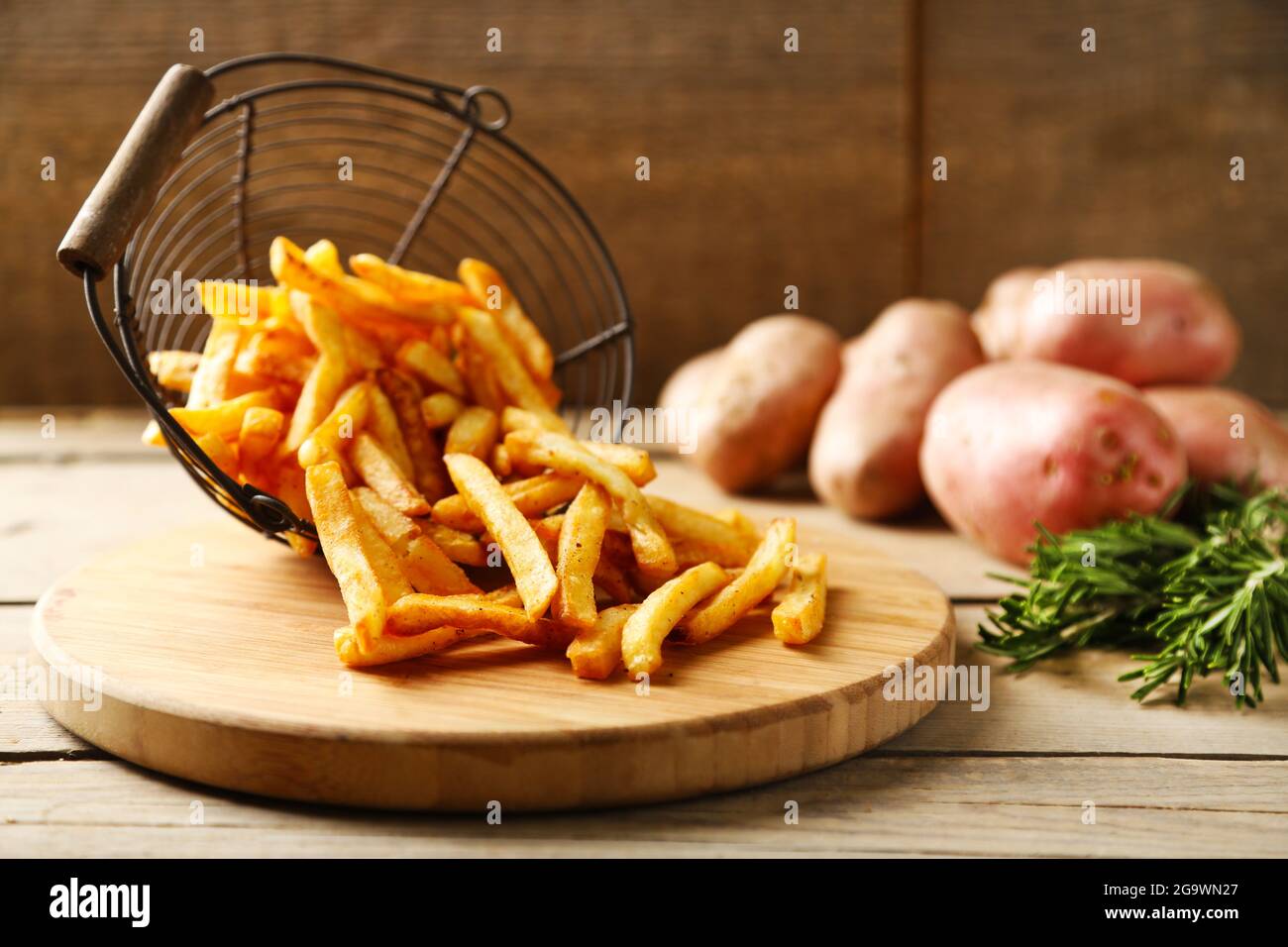 Cortar patatas en tabla de madera con patatas en metal cesta en el fondo  Fotografía de stock - Alamy