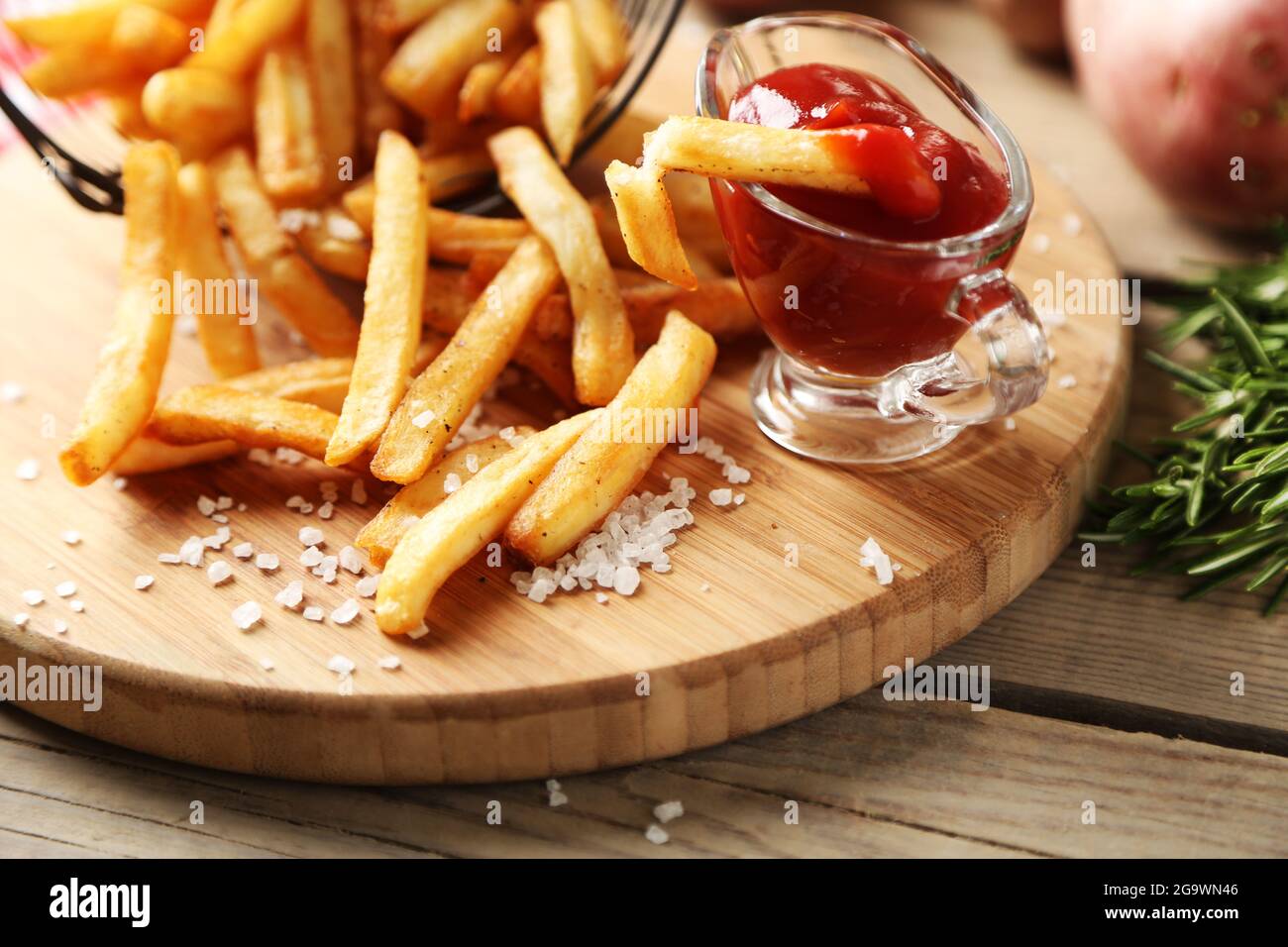 Cortar patatas en tabla de madera con patatas en metal cesta en el fondo  Fotografía de stock - Alamy