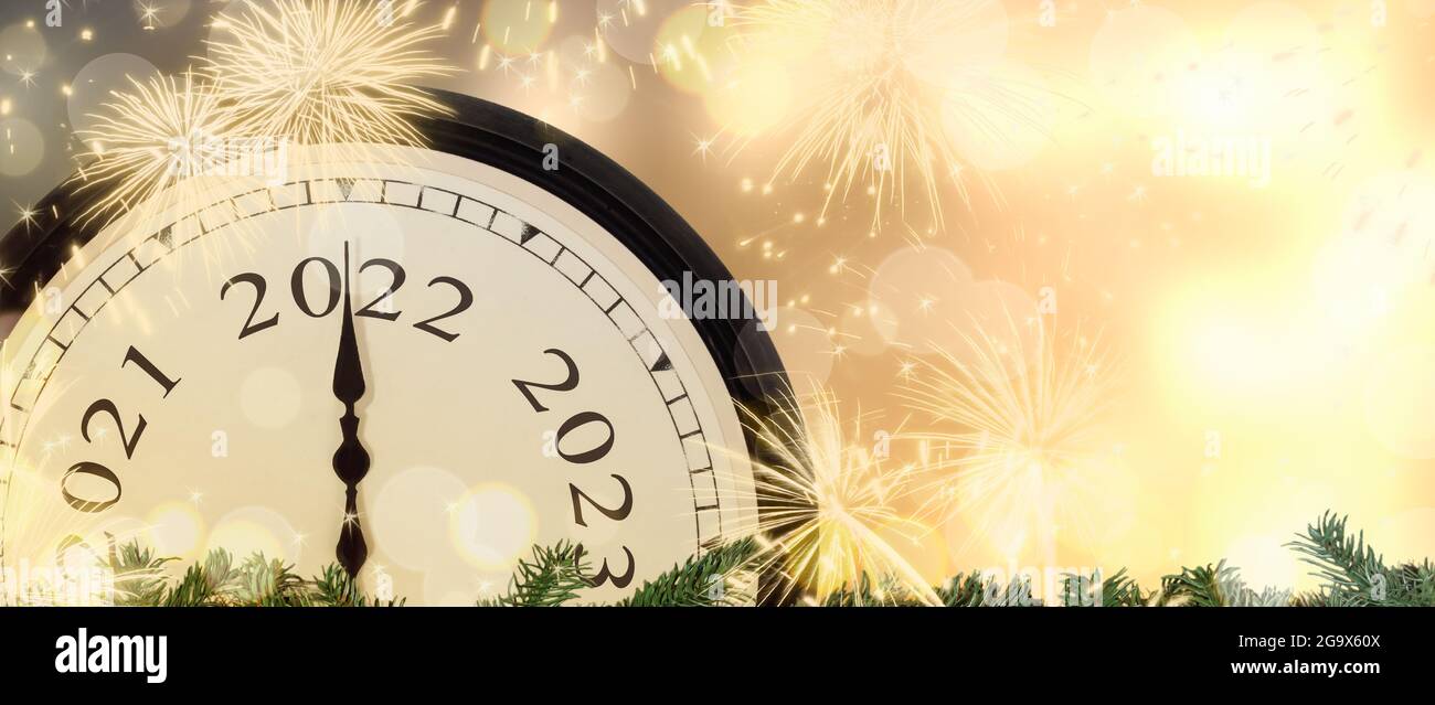 Reloj de Año Nuevo 2022 y fuegos artificiales de fondo. Foto de stock