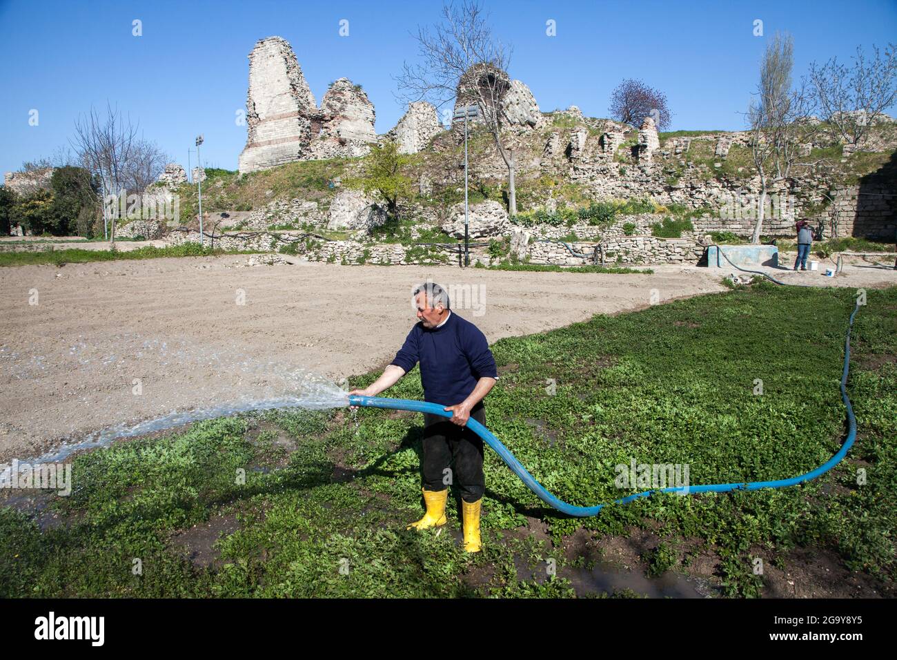 Fatih,Estambul,Turquía - 04-02-2017:Vista de las históricas murallas bizantinas con agricultor trabajando en el campo de las verduras Foto de stock