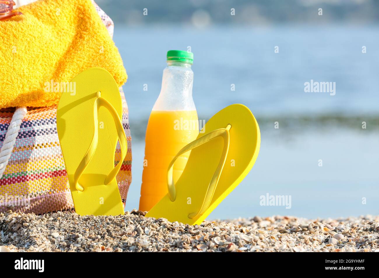 Chanclas, bolsa, toalla y botella de jugo en la playa de mar, primer plano  Fotografía de stock - Alamy