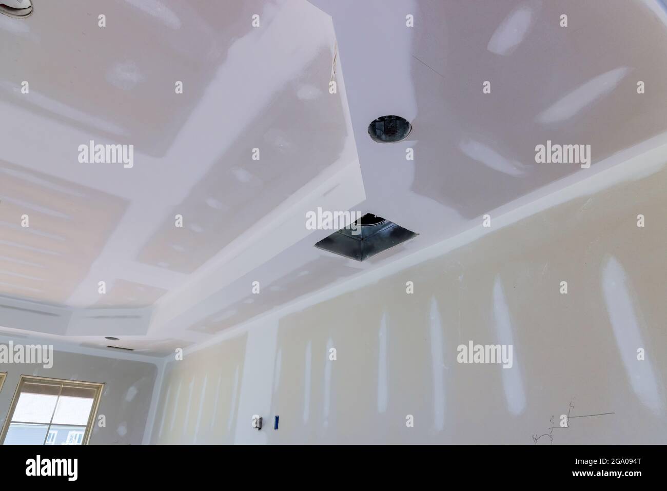 El maestro está aplicando masilla blanca en una pared y manchando con una  espátula en una sala de renovación de la casa durante el día