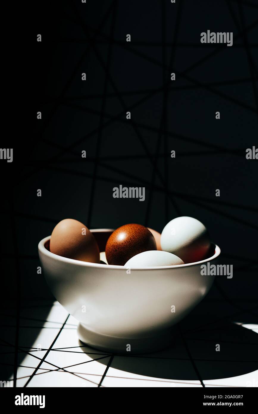 Vista de primer plano de huevos de varios colores en un recipiente de cerámica Foto de stock