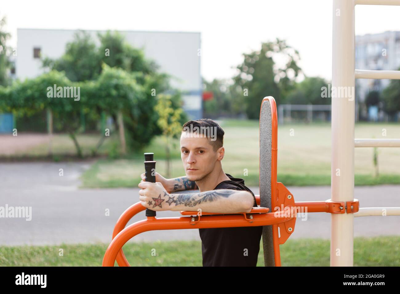 El hombre entrena fuera en el parque con equipos deportivos Foto de stock