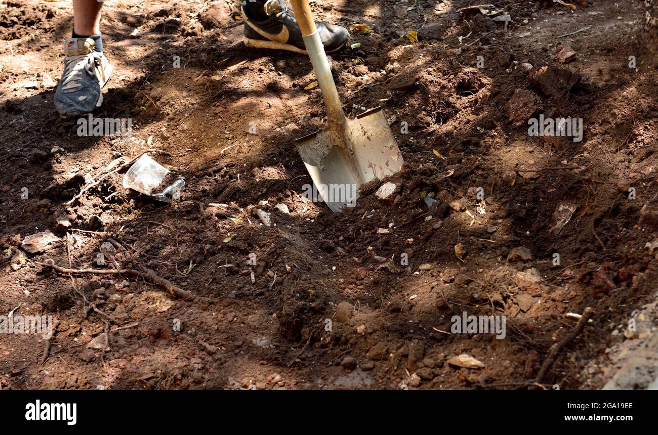 Persona excavando con pala en terreno pedregoso y rocoso Foto de stock