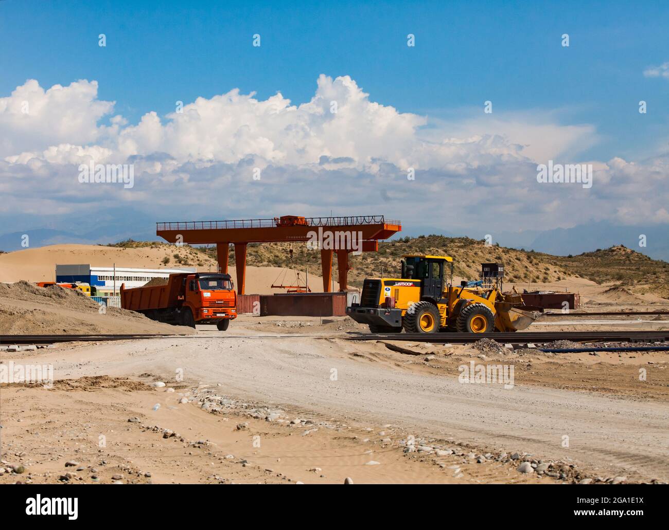 Altynkol, Kazajstán - 05 de junio de 2012: Estación de tren Altynkol. Construcción del terminal de carga de contenedores de trenes. Grúa de gantry roja y bulldozer XCMG Foto de stock