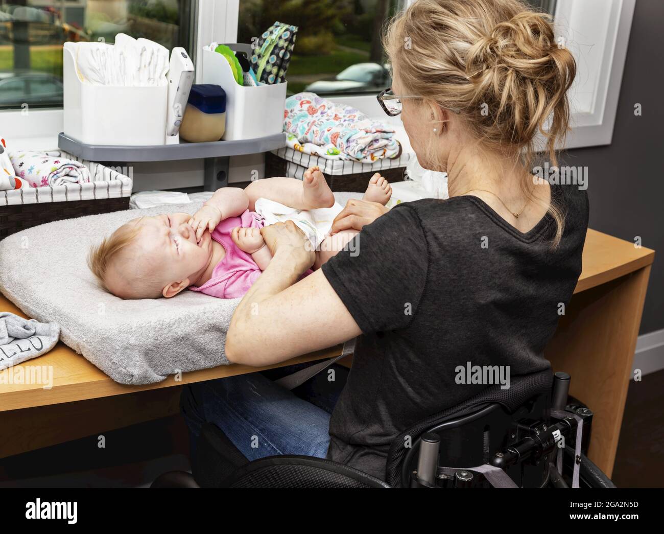 Una madre en silla de ruedas cambia el pañal de su bebé en una mesa para  cambiarse en un vivero; Edmonton, Alberta, Canadá Fotografía de stock -  Alamy