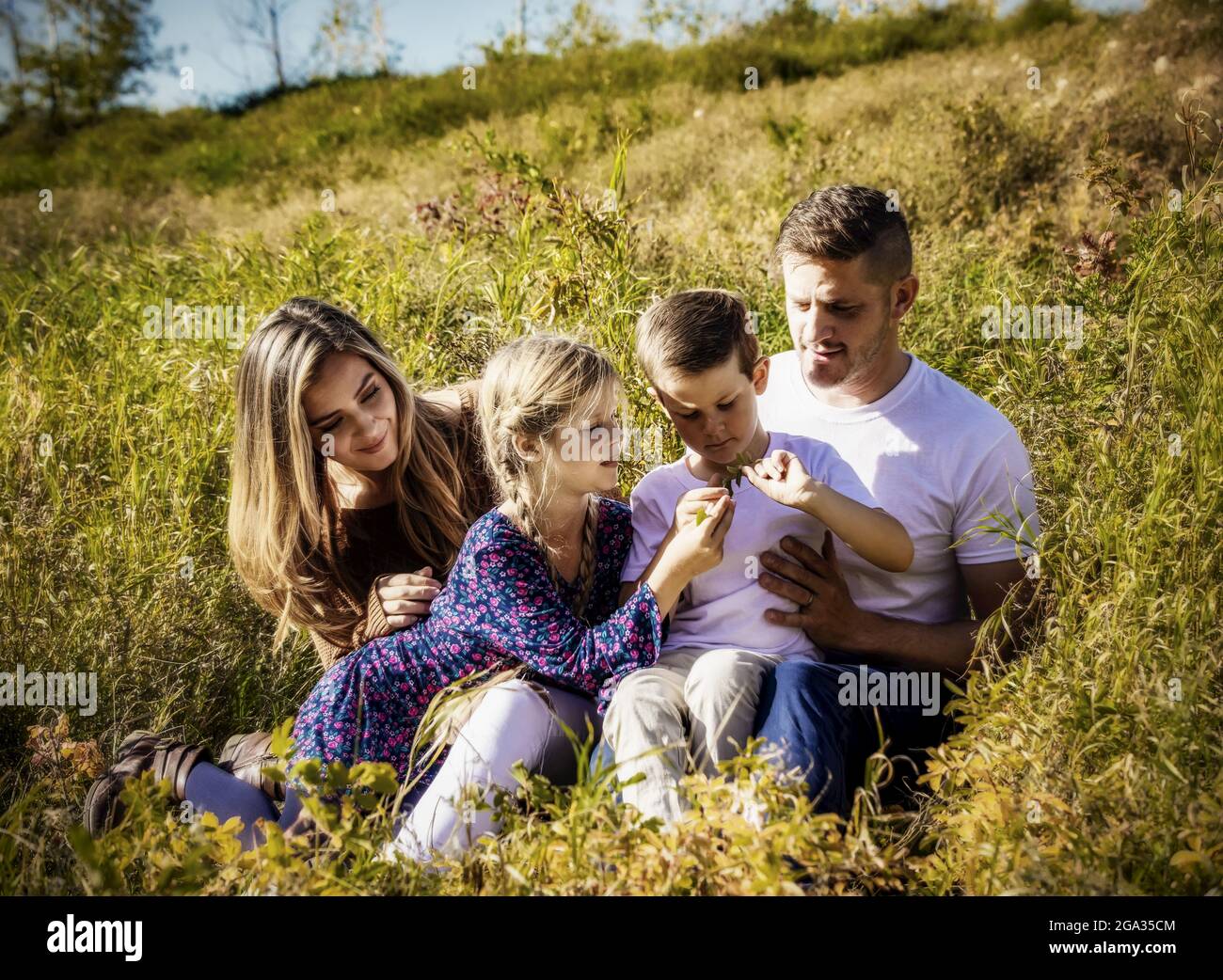 Una familia pasando tiempo de calidad juntos al aire libre en un parque de la ciudad durante la temporada de otoño; Edmonton, Alberta, Canadá Foto de stock