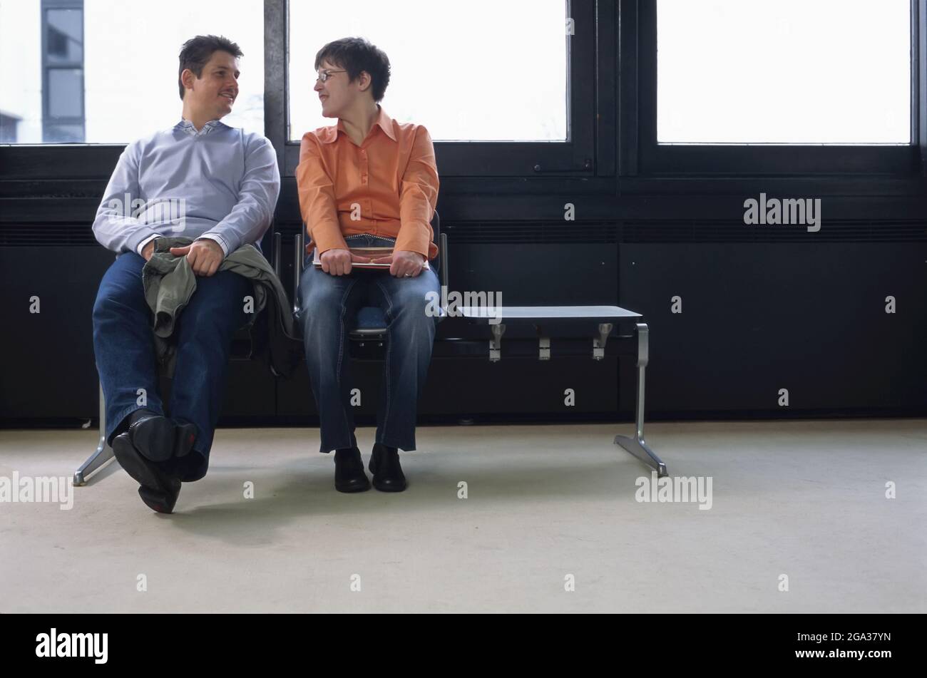Un hombre y una mujer con necesidades especiales se sientan mirándose unos a otros de una manera coqueteando; Alemania Foto de stock