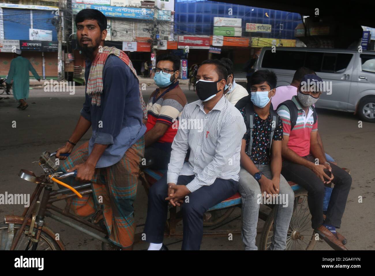Dhaka, Bangladesh. 29th de julio de 2021. La vida pública en la capital, Dhaka, no se detiene ni siquiera en el severo bloqueo. Aunque todo está cerrado en el encierro, muchas personas están saliendo en caso de emergencia o innecesario. Las máscaras son relativamente usadas, pero la renuencia a mantener la distancia social se ve en casi todo el mundo. Aunque algunas oficinas tienen su propio sistema de transporte, la mayoría de los pasajeros se enfrentan a problemas debido al cierre del transporte público. Van al destino en rickshaw o van o algunos en bicicleta. (Imagen de crédito: © Md. Rakibul Hasan/ZUMA Press Wire) Foto de stock