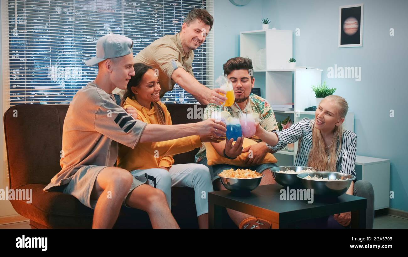 De cerca, los amigos felices se animan unos con otros con cócteles de hielo seco. Ellos tienen un buen tiempo juntos, sonriendo y levantando puños apretados. Foto de stock