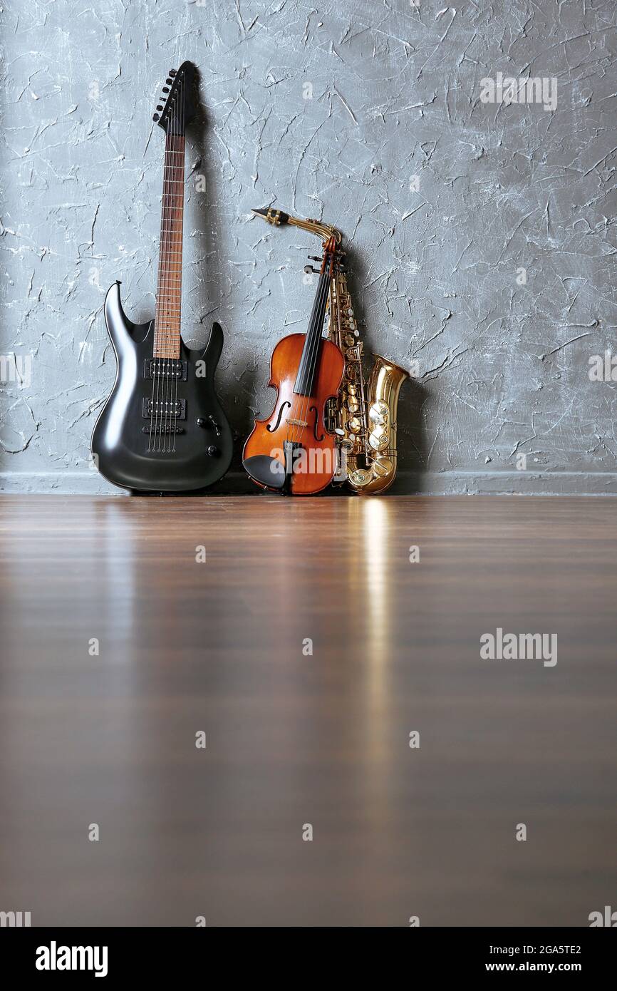 Guitarra eléctrica, saxofón y violín sobre fondo gris de pared Fotografía  de stock - Alamy