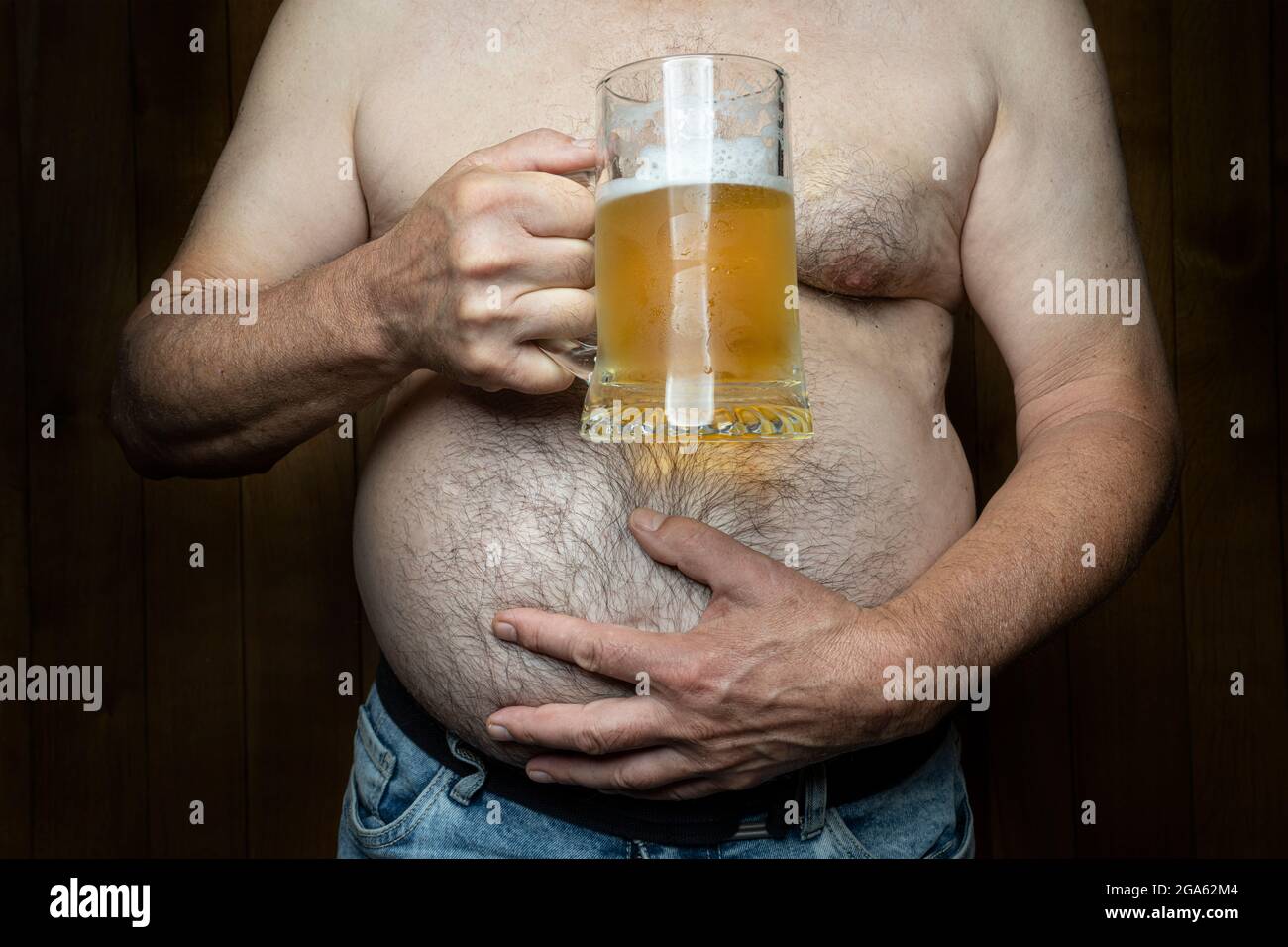 un hombre con un gran vientre con una taza de cerveza en su mano Foto de stock