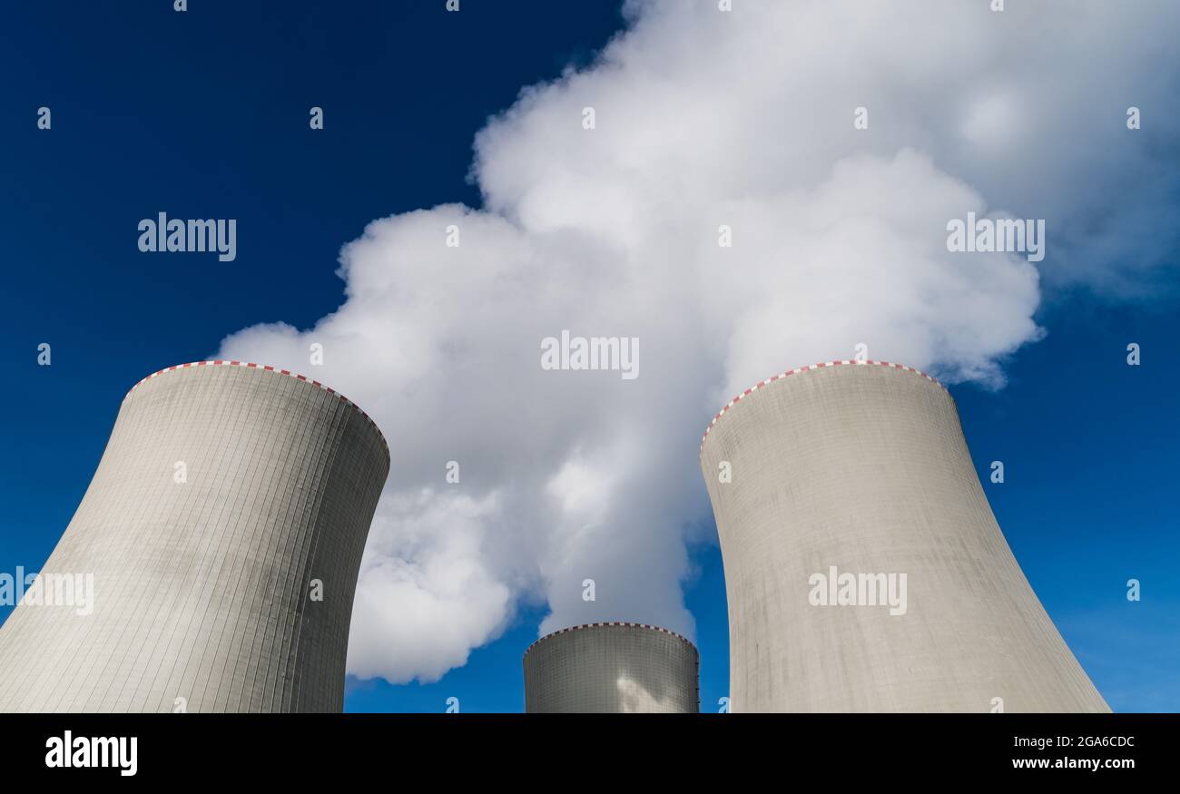 Primer plano de las torres de refrigeración de la central nuclear que se erige en una columna blanca de vapor de agua. Eliminación del calor. Moderna estación generadora en un cielo azul. Ecología. Foto de stock