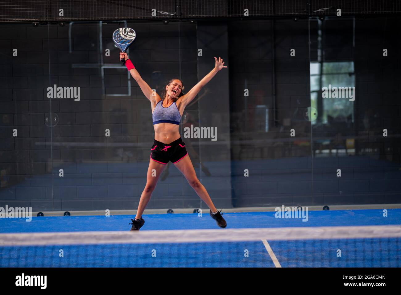 Retrato de una hermosa niña wimmer exultando en una pista de padel de tenis cubierta Foto de stock