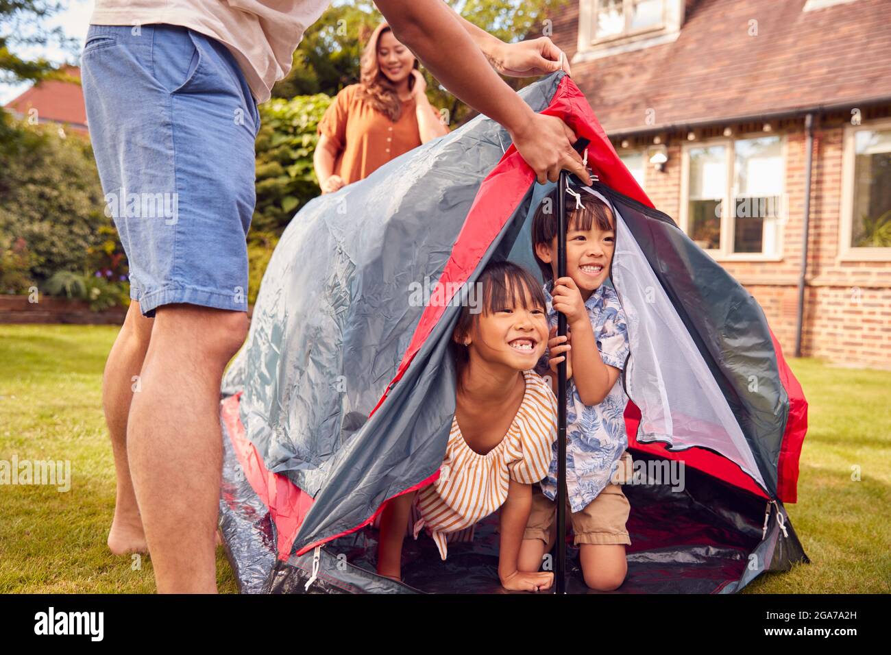 Familia asiática en el jardín en casa que pone tienda para el viaje del camping juntos Foto de stock