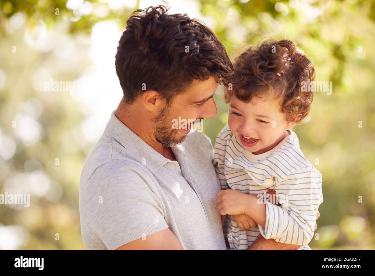 Padre amoroso con el hijo Diversión en el parque que lo sostiene en el aire  contra el fondo frondoso Fotografía de stock - Alamy