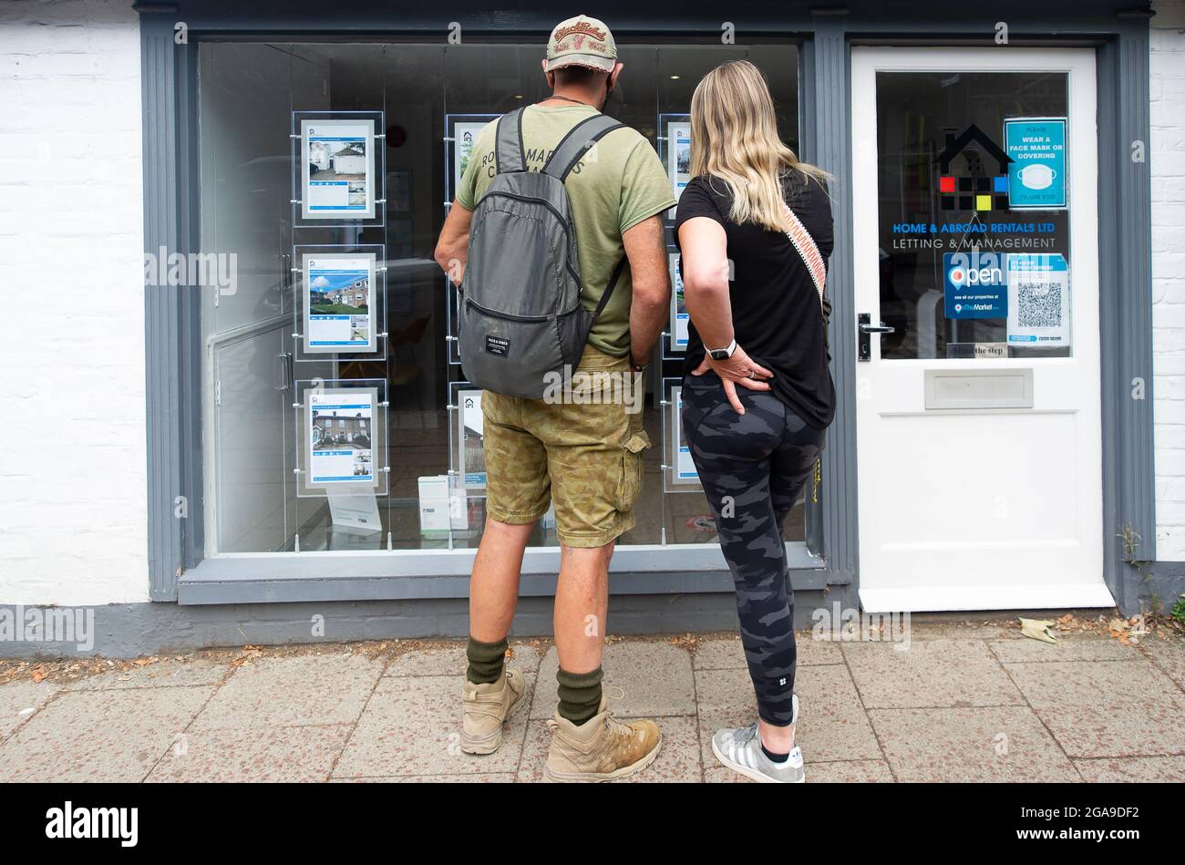Berkhamsted, Hertfordshire, Reino Unido. 28th de julio, 2021.UN par busca casas a la venta en una ventana de agentes de bienes raíces. Crédito: Maureen McLean/Alamy Foto de stock