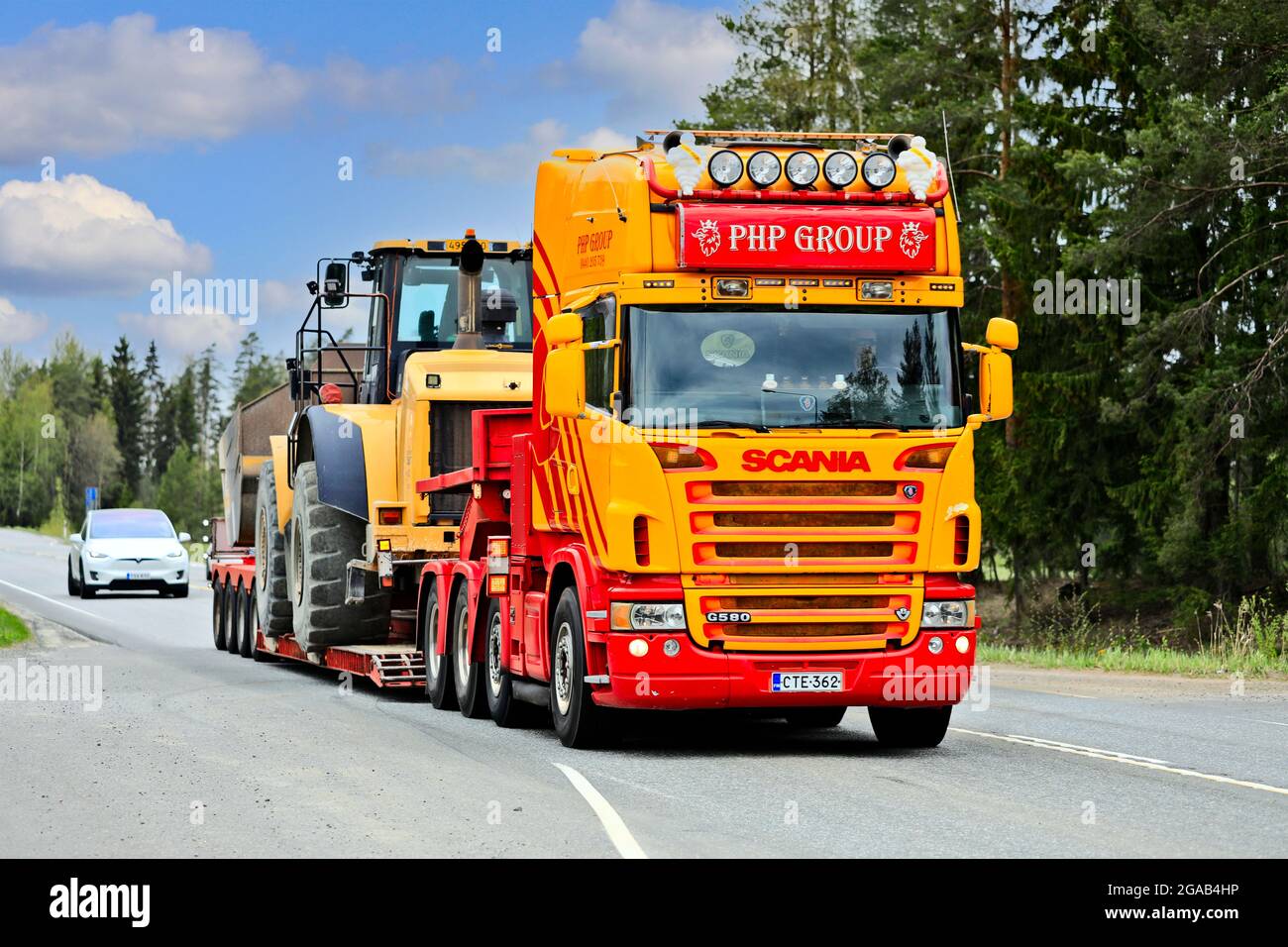 Scania G580 personalizada camión del grupo PHP delante de remolque de cuello de cisne transporta la pala de ruedas Cat en la autopista 2. Jokioinen, Finlandia. 14 de mayo de 2021. Foto de stock