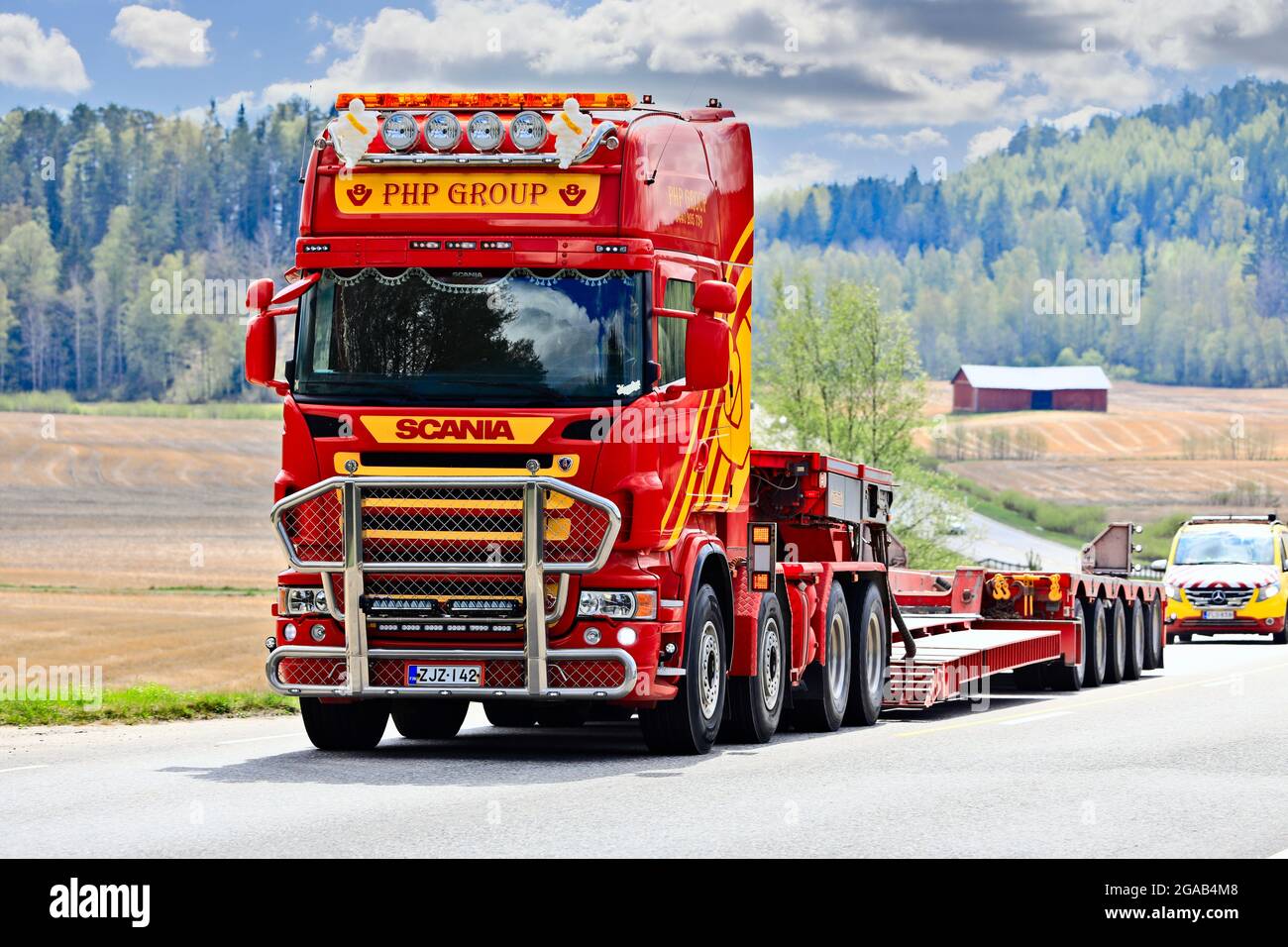 Scania camión del grupo PHP delante del remolque de cuello de cisne regresa de la entrega de una carga sobredimensionada, seguido por el vehículo escolta. Salo, Finlandia. 15 de mayo de 2021 Foto de stock