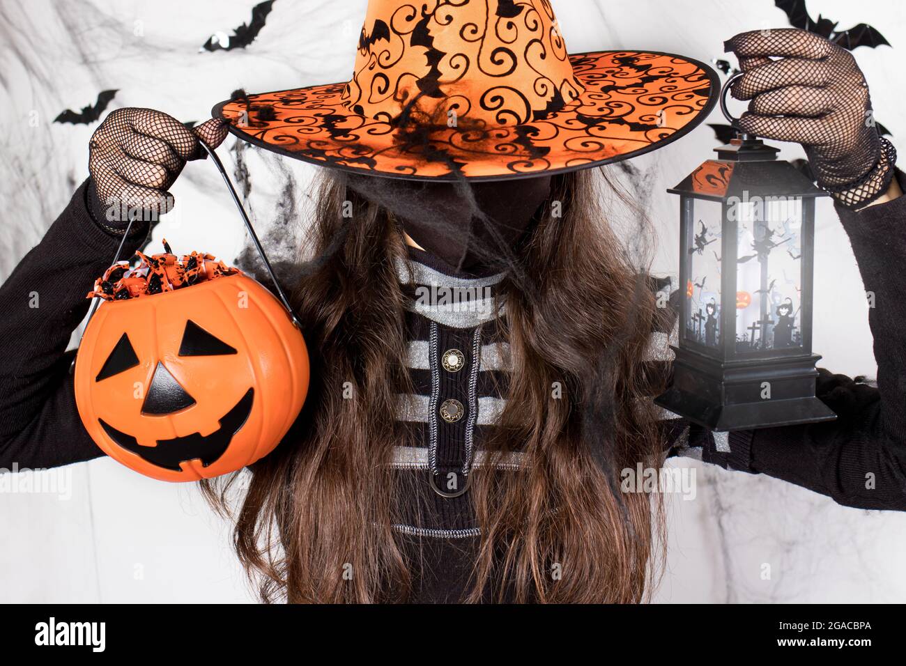 Halloween enmascaró a la gente. Una mujer con un traje de bruja en una  máscara protectora sostiene una calabaza con caramelo y una linterna  luminosa. Durante la cacerola del coronavirus Fotografía de