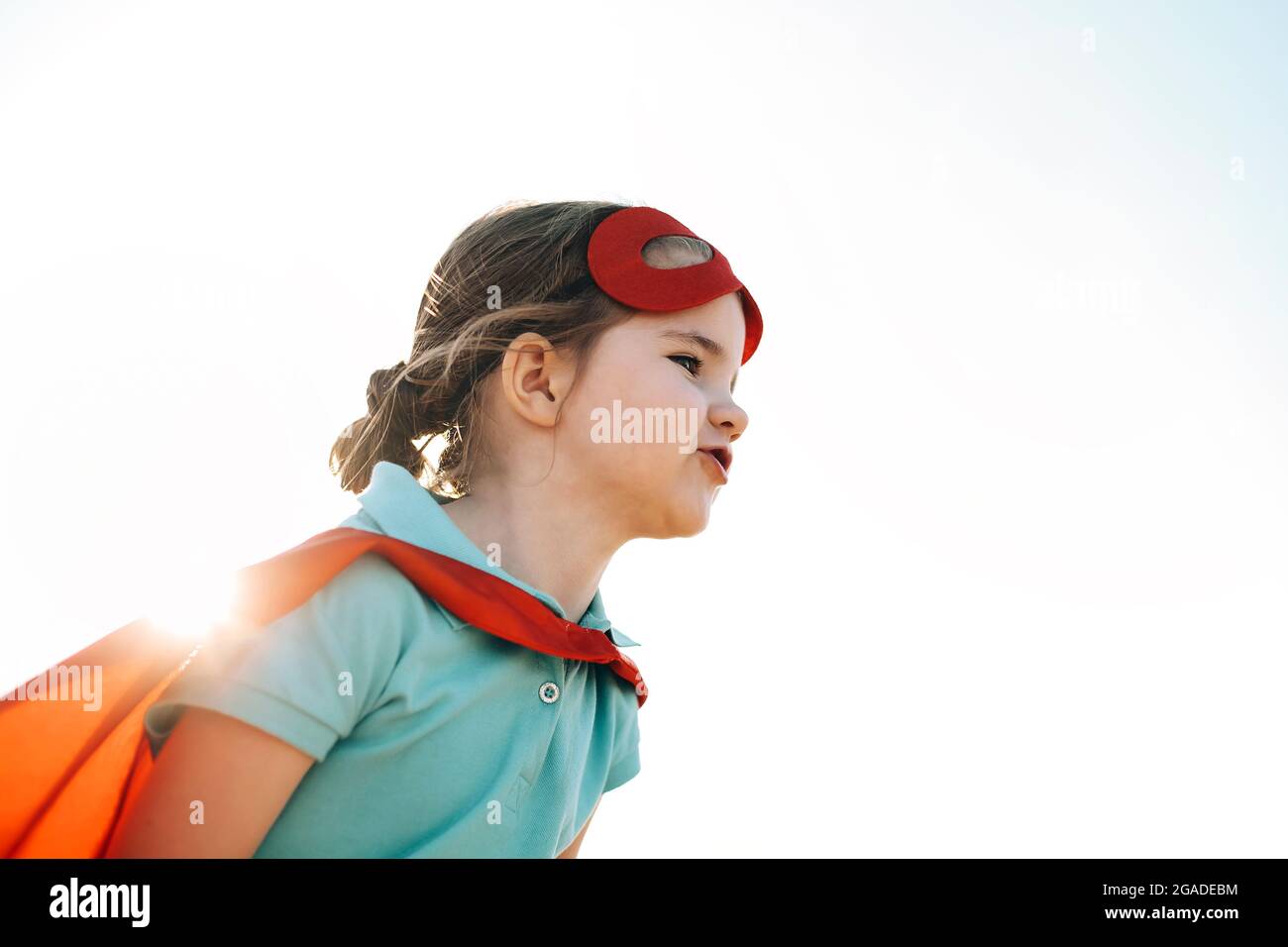 Retrato de un niño superhéroe contra el fondo del cielo azul. Concepto de alegría e infancia Foto de stock