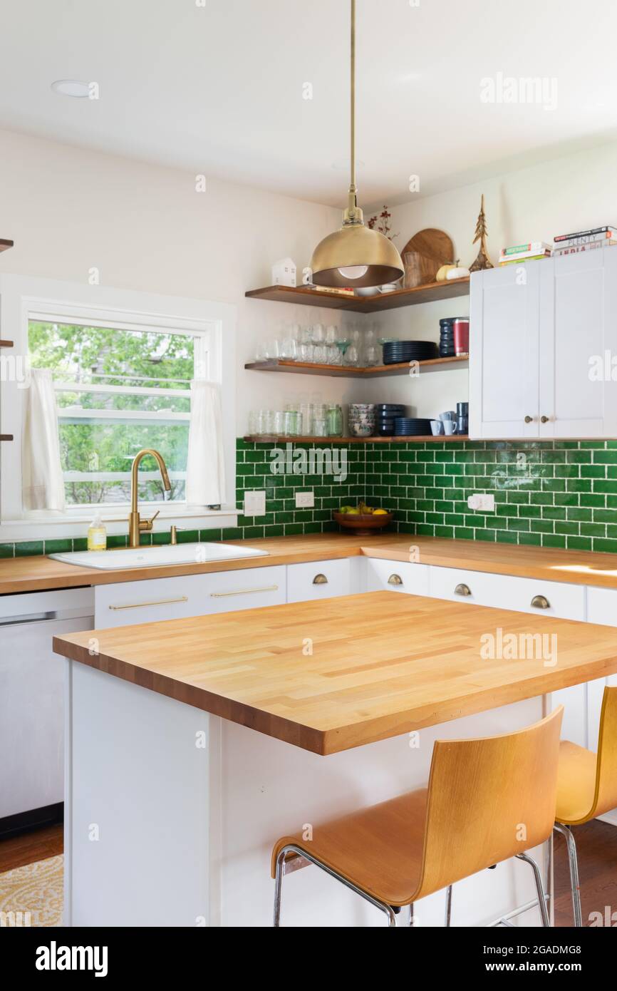 Una cocina renovada con armarios blancos, una encimera de madera natural,  sillas sentadas en la isla, y un chapoteo de azulejos verde del metro  Fotografía de stock - Alamy