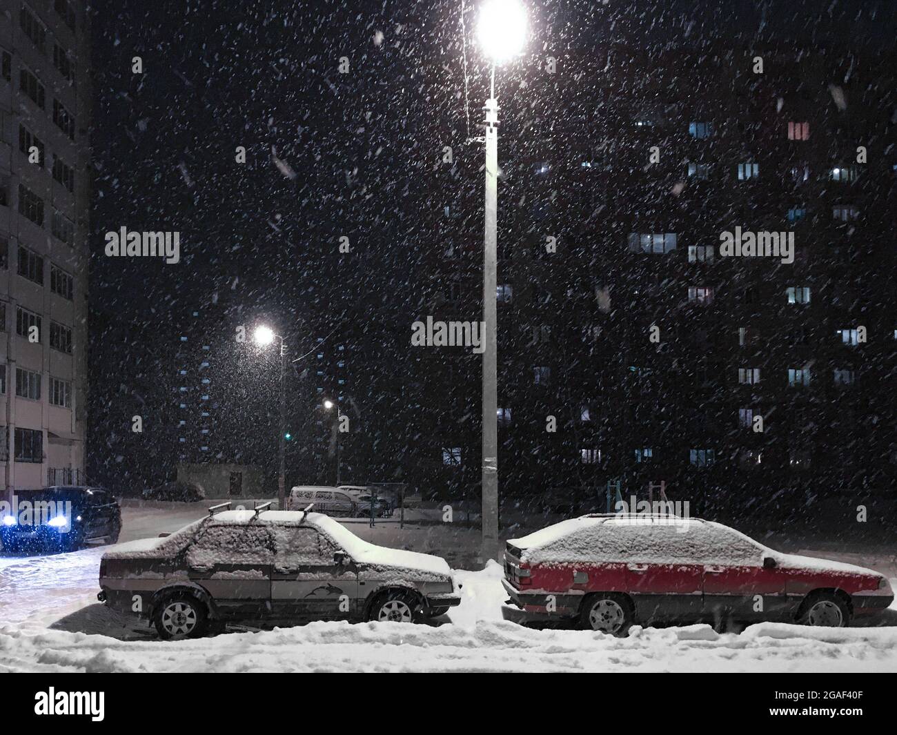 Escena nocturna de la calle tormenta de nieve, ventisca con los coches Foto de stock