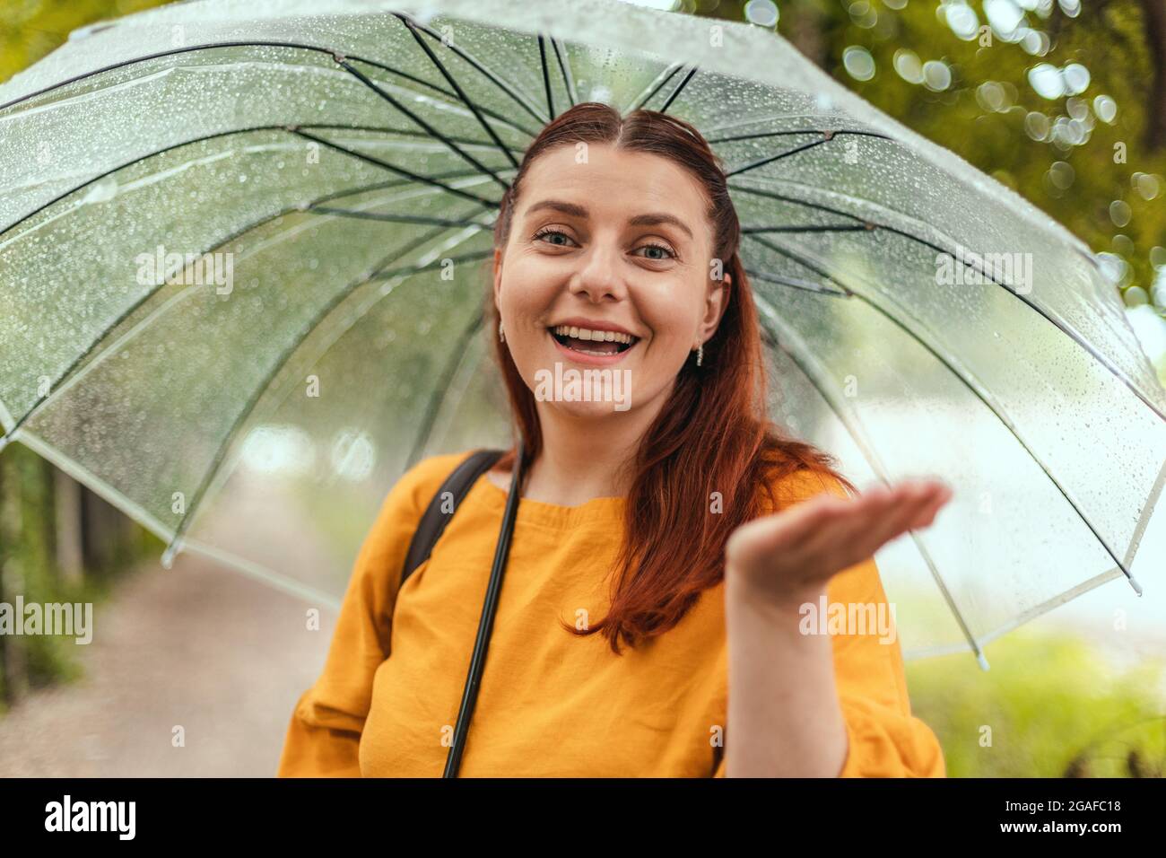 Una hermosa mujer se encuentra bajo un paraguas transparente y se estira  por su mano, atrapando gotas de agua. Banner horizontal, espacio de copia  Fotografía de stock - Alamy
