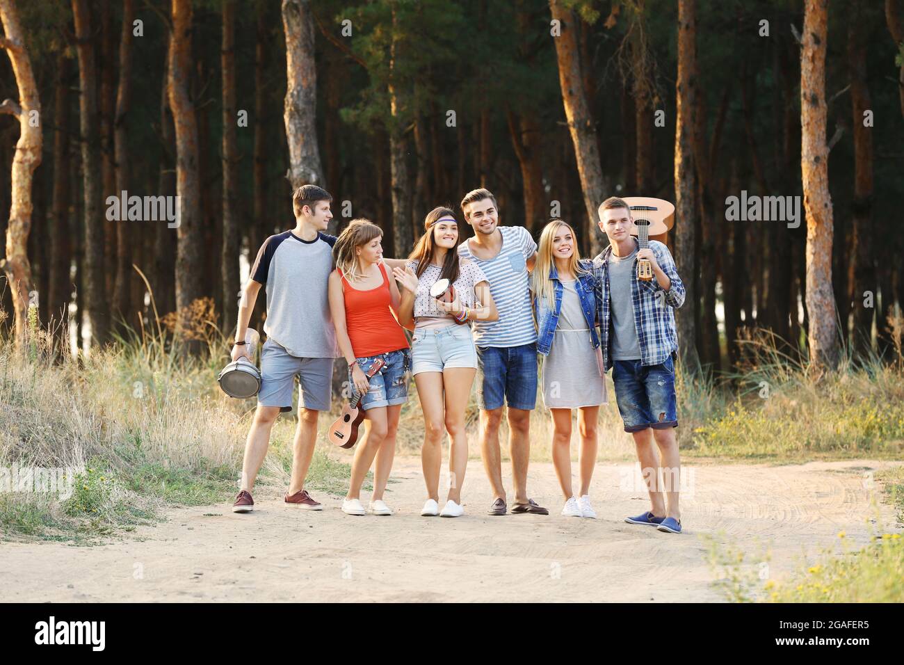 Feliz sonriendo amigos con instrumentos de música relajante en el bosque al  aire libre Fotografía de stock - Alamy